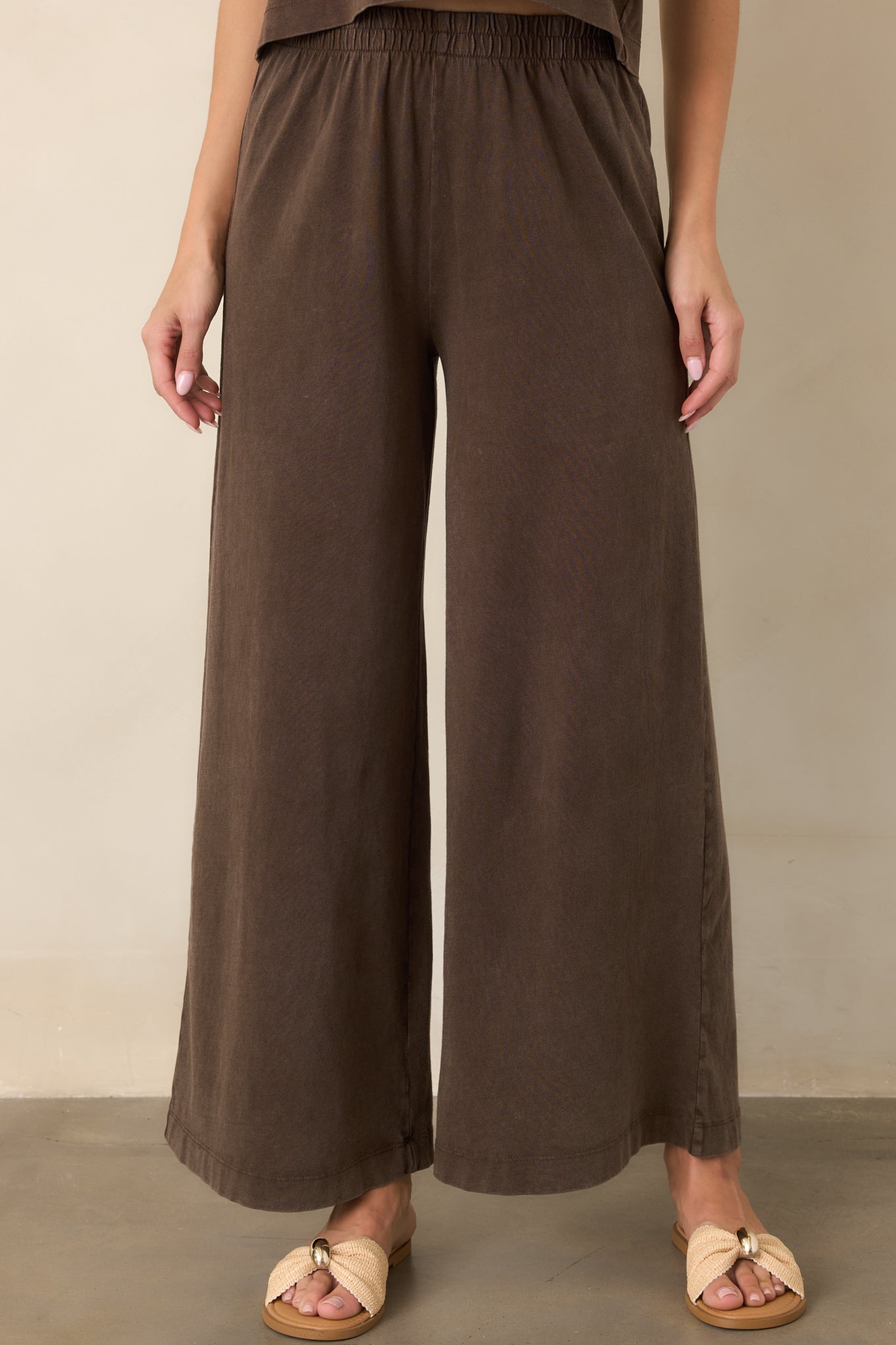 Dark chocolate brown wide-leg pants showcasing the smooth waistband and softly structured fabric through the hips and legs.