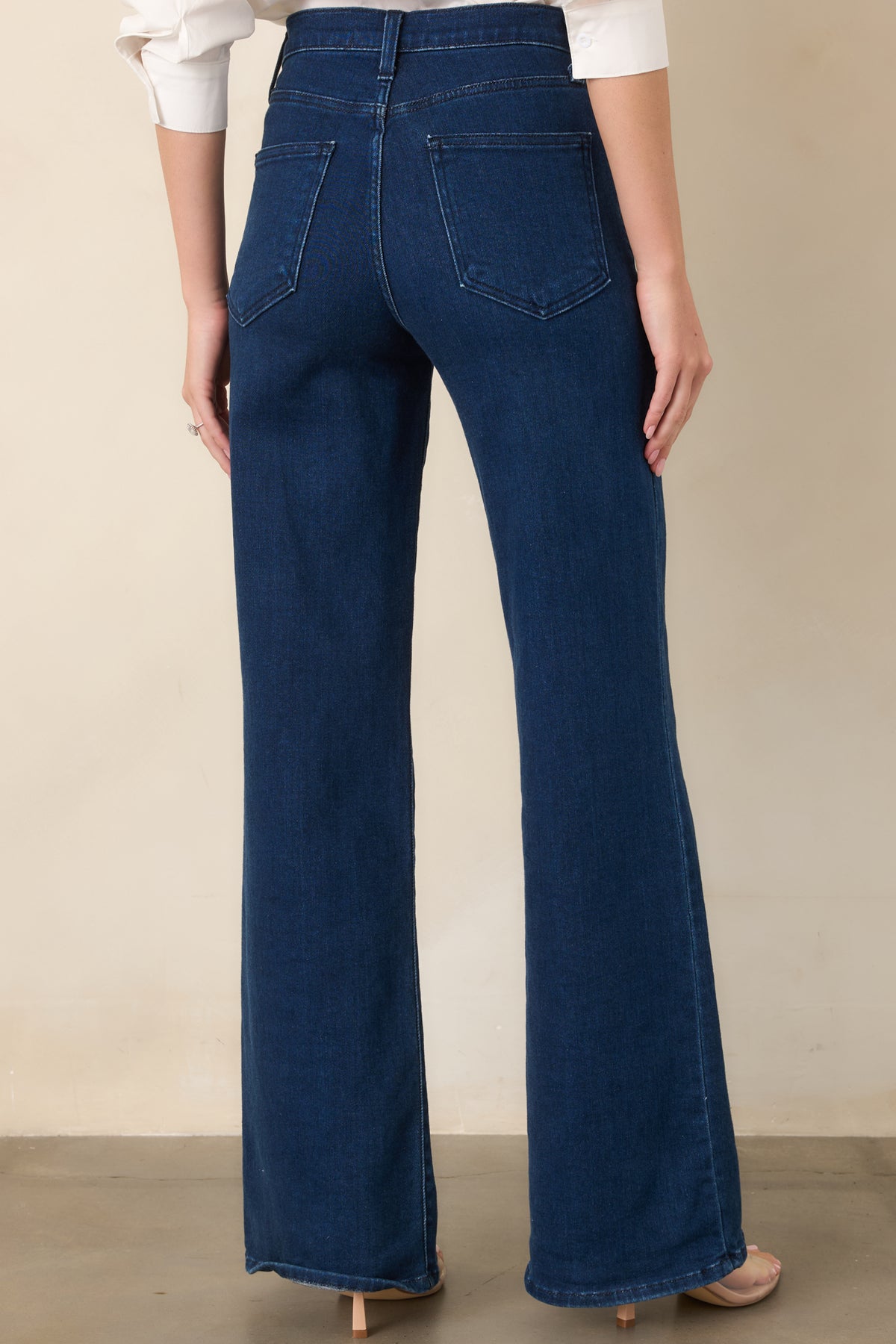 Rear view of the dark denim pants featuring two practical back pockets, a high-set waistband, belt loops, and generously cut wide legs.