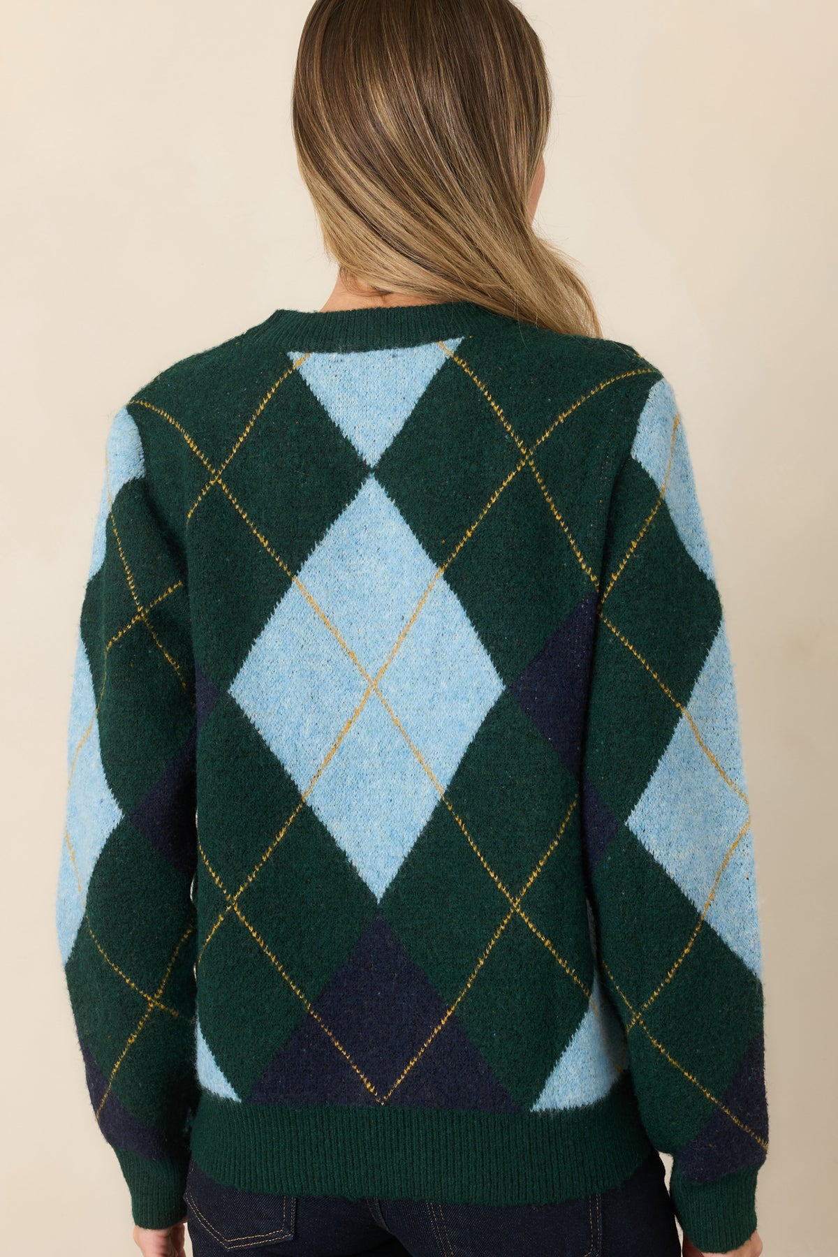 Rear view of the dark green knit sweater highlighting its geometric diamond pattern, long sleeves, relaxed fit, and ribbed hem.