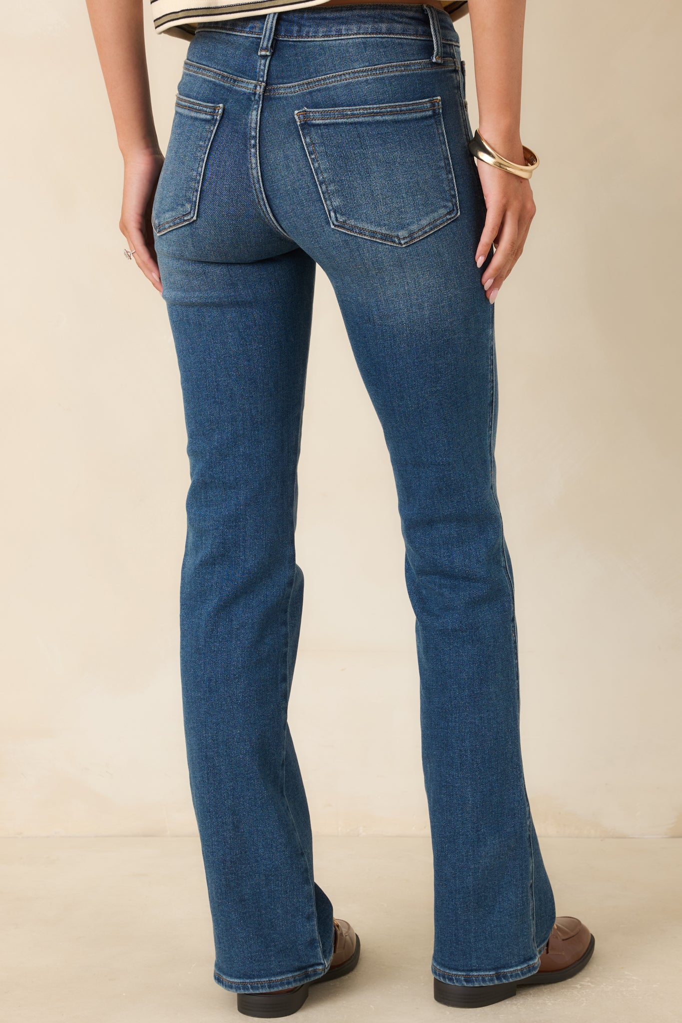 Rear view of the dark indigo bootcut jeans featuring two back pockets, belt loops, subtle fading, and a fitted silhouette through the hips and thighs.