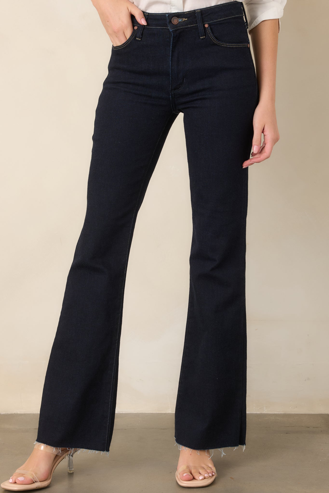 Close view of the dark indigo jeans highlighting the high-rise waistband, belt loops, button closure, and smooth stretch denim.
