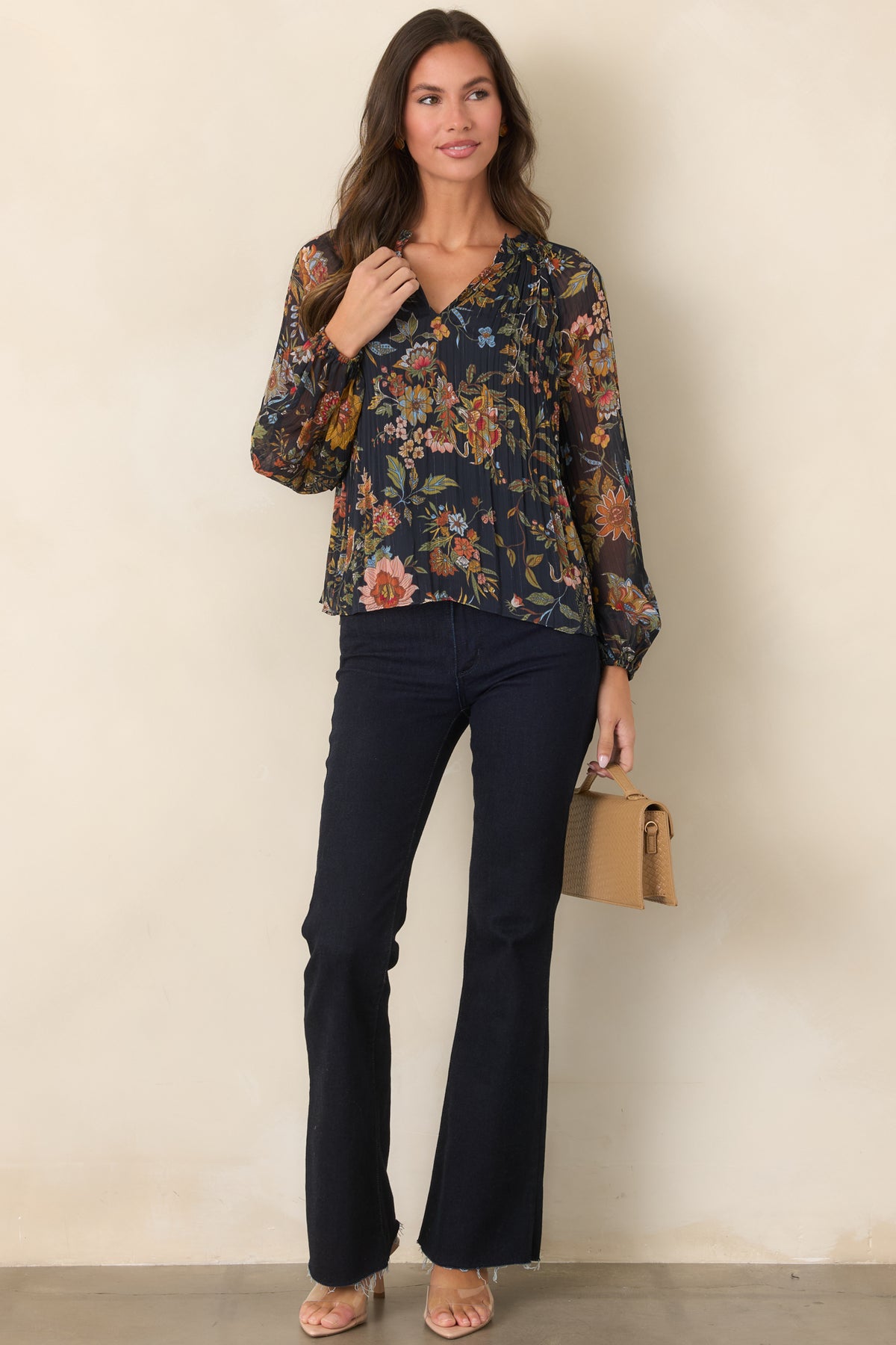 Woman wearing dark indigo high-rise flare jeans with a raw hem, styled with a navy floral blouse.