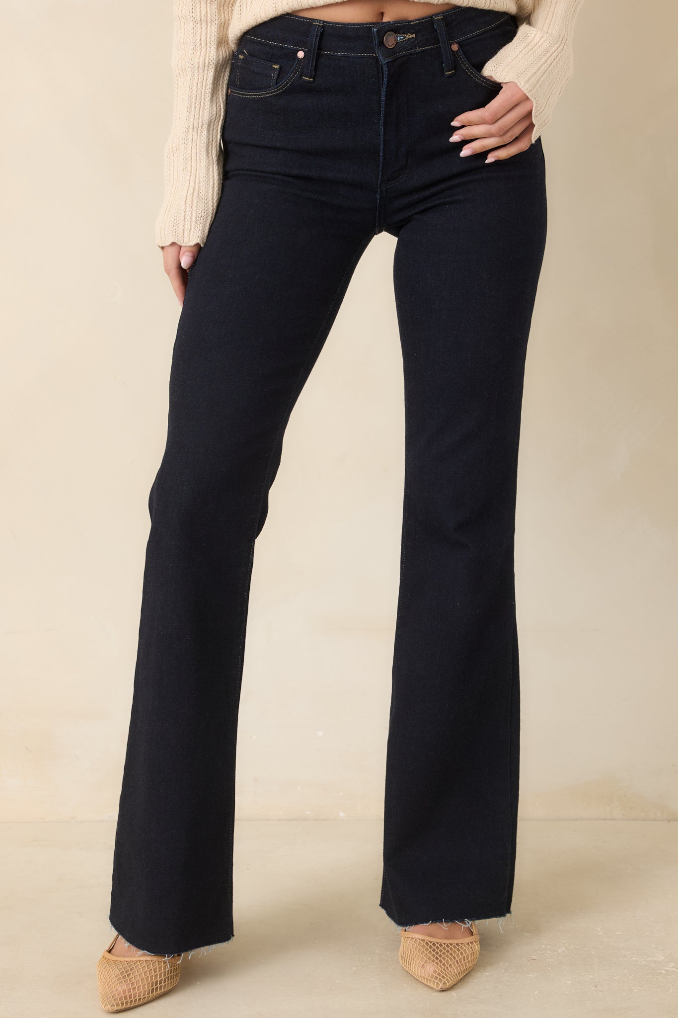 The front of these dark indigo jeans highlights the high-rise waistband and fitted upper shape.