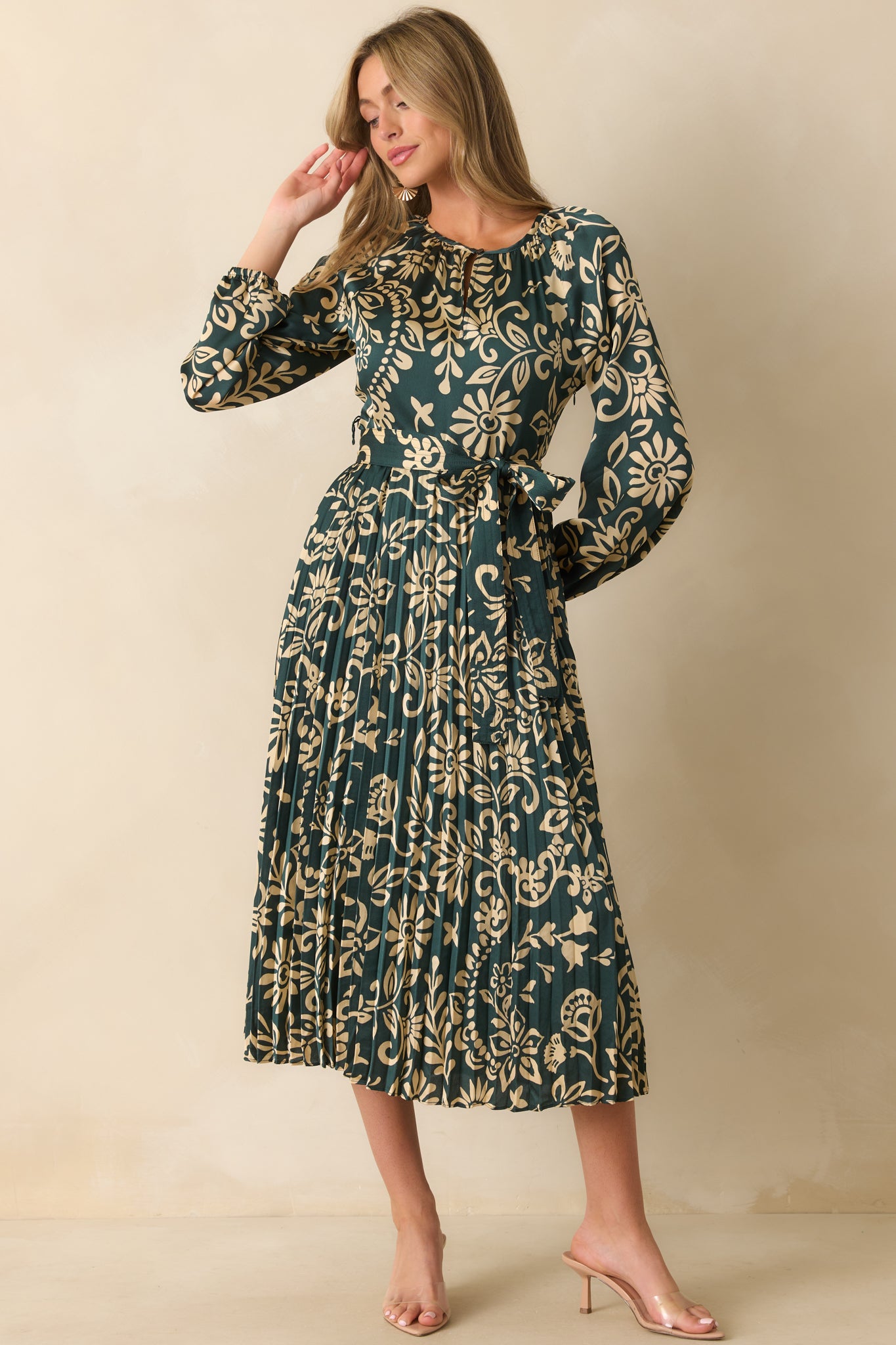 Beige floral print stands out across the dark teal fabric with a cinched waist detail.