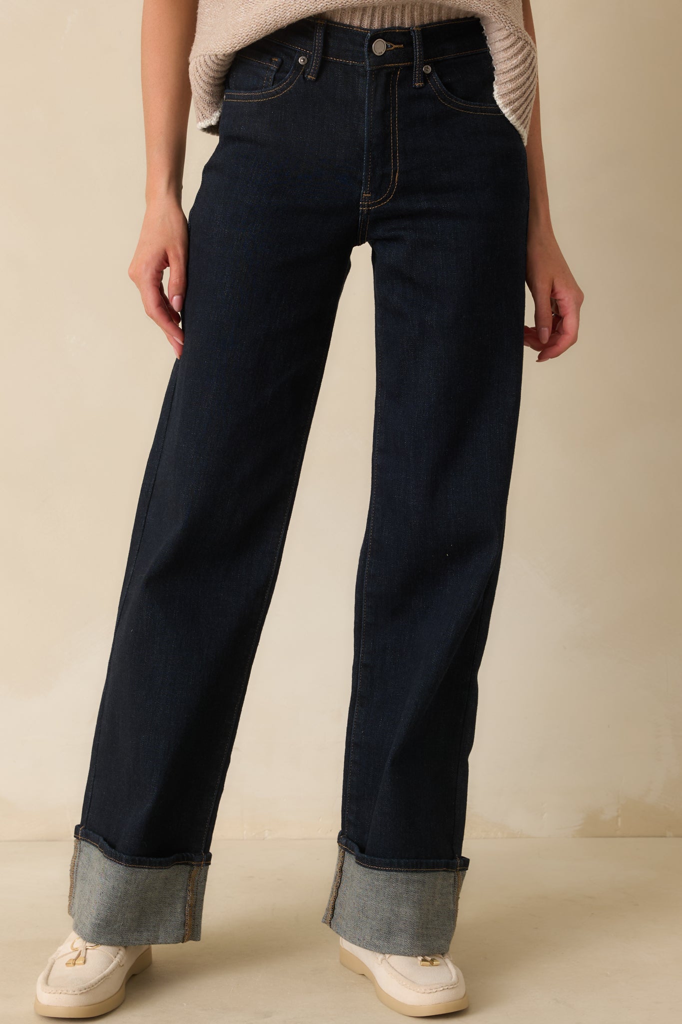Dark wash denim jeans with high-rise waist, wide-leg silhouette, five-pocket design, and wide cuffed hems.