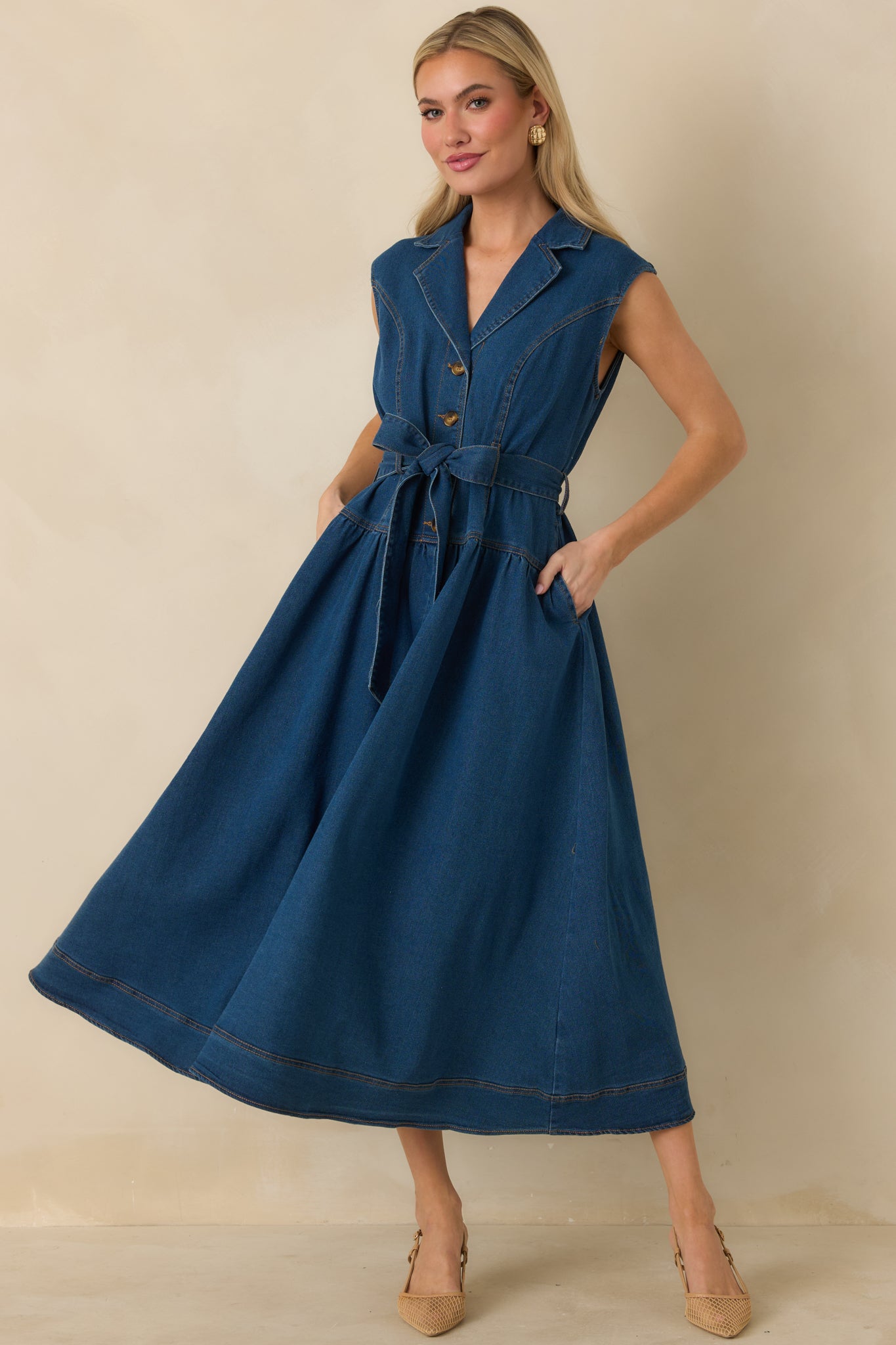 Dark wash denim midi dress with sleeveless design, collared neckline, and gold-tone button-front closure.