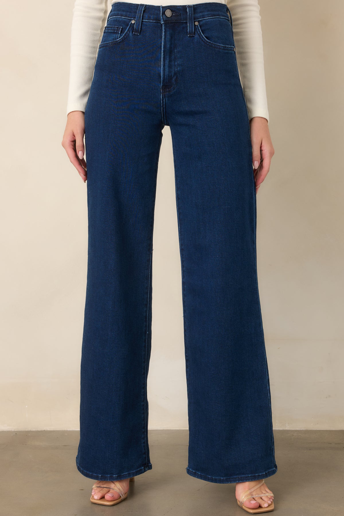 Detailed view of the dark wash denim fabric, high-rise waist, and classic five-pocket-inspired construction.