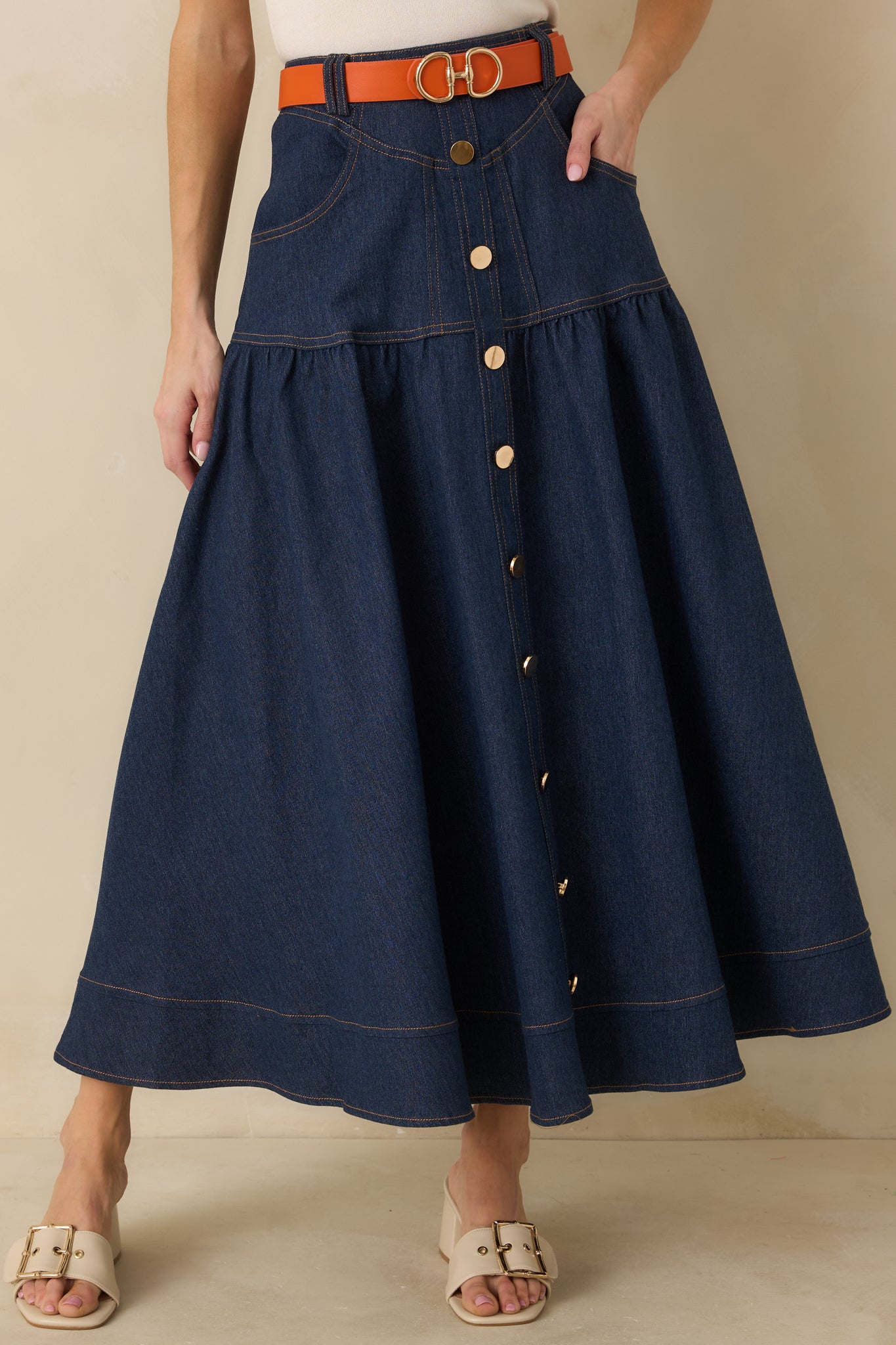 Close-up of the dark wash denim skirt showing the button closure, contrast topstitching, and structured waistband.
