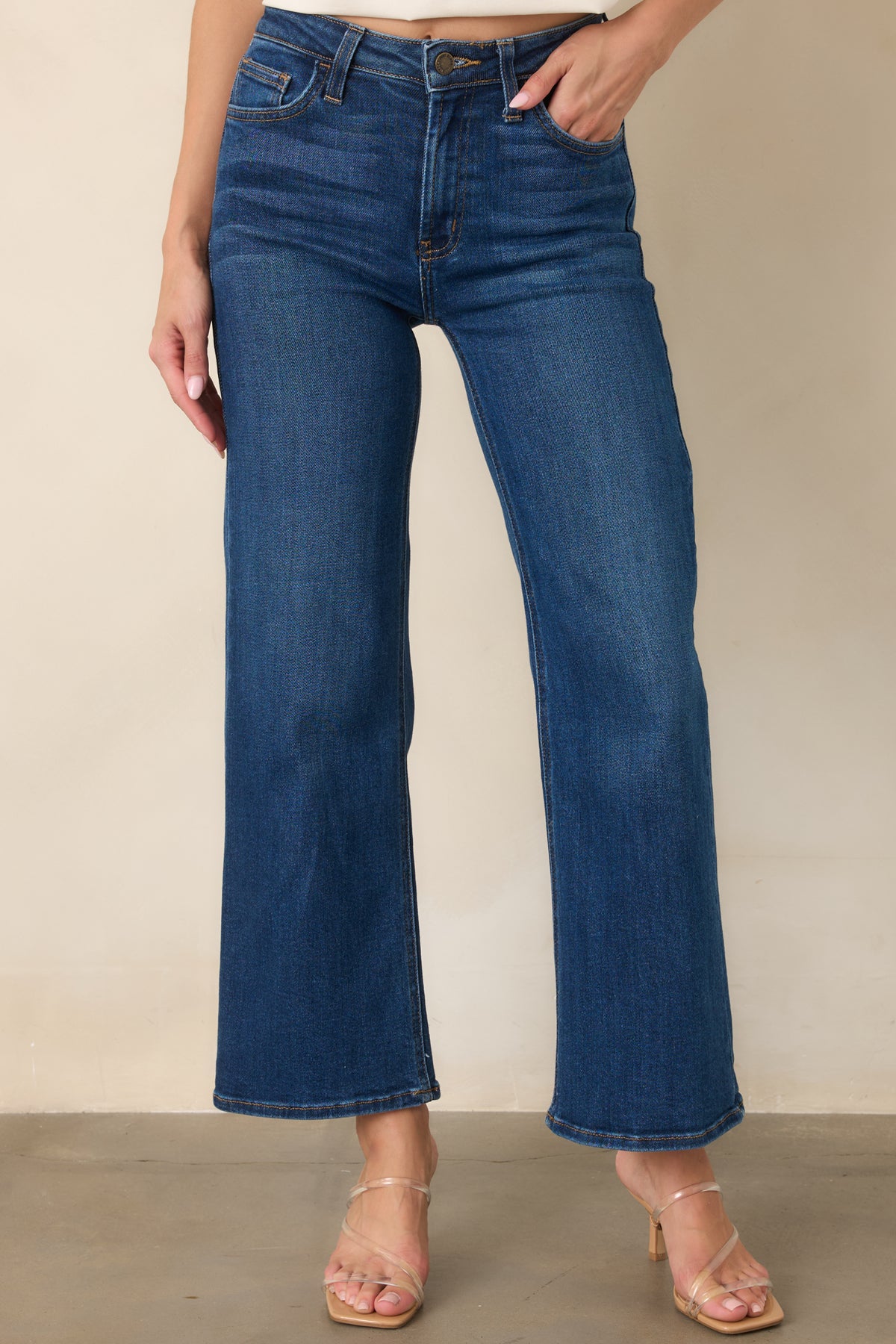 Close-up of the dark wash denim featuring the high waistband, belt loop construction, and classic front pocket detailing.