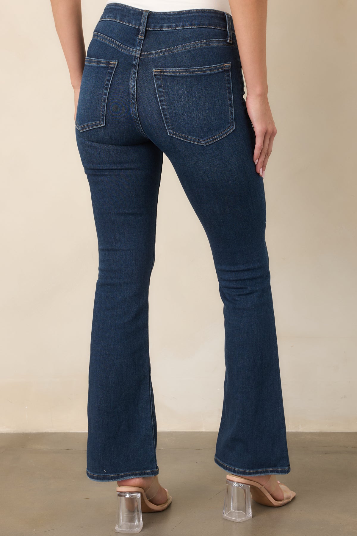 Rear view of the dark-wash flare jeans featuring traditional back pockets, contrast stitching, a mid-rise waist, and subtly flared legs.
