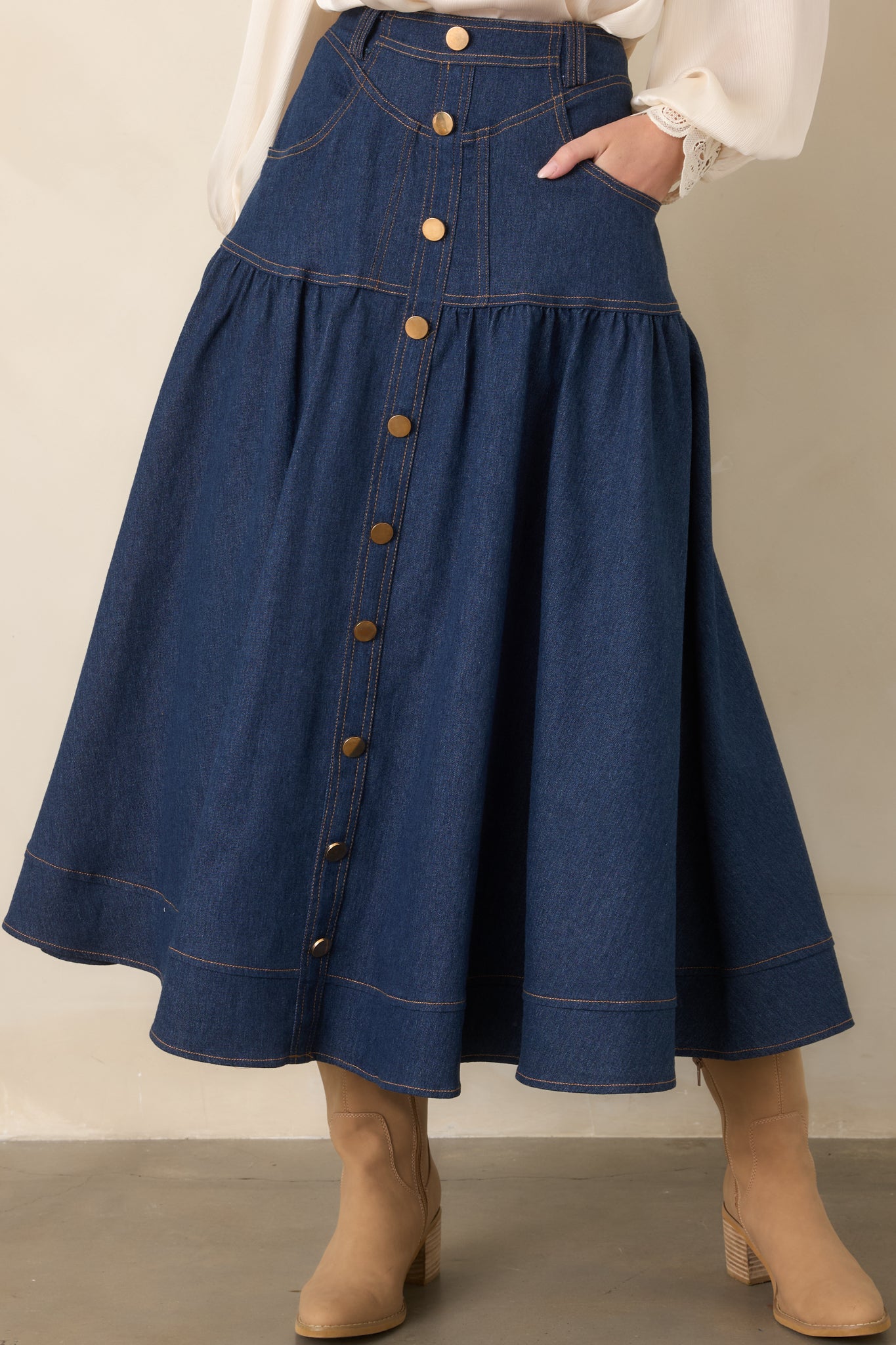 Dark wash skirt highlighting its high-rise waistband, gold-tone buttons, belt loops, and tailored denim construction.