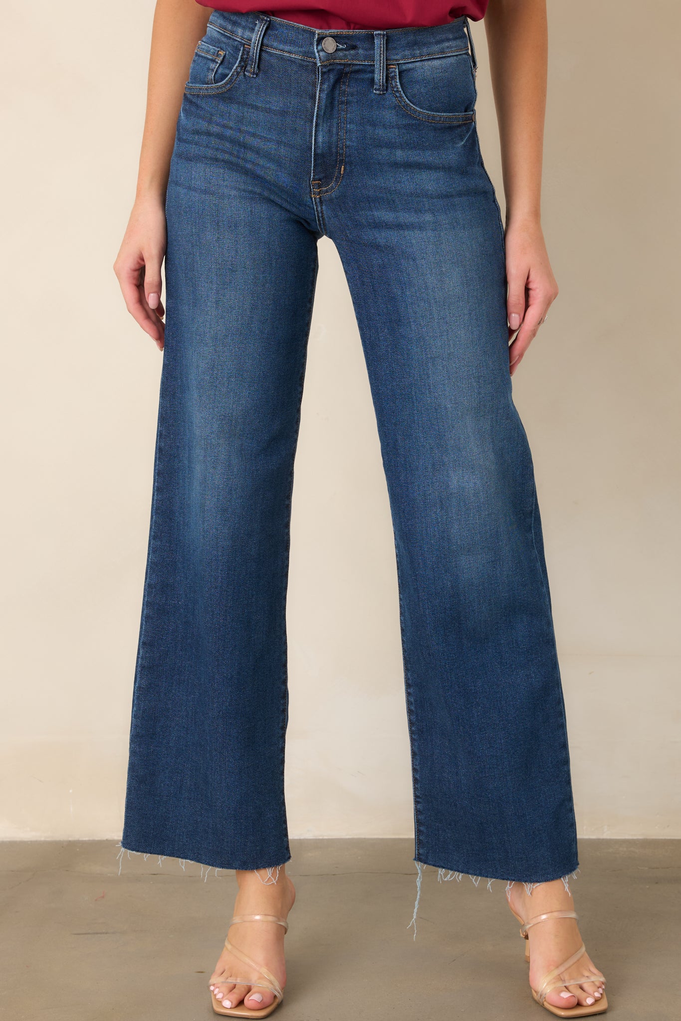 Close view of the dark wash jeans highlighting the high-rise waistband, button closure, and functional belt loops.