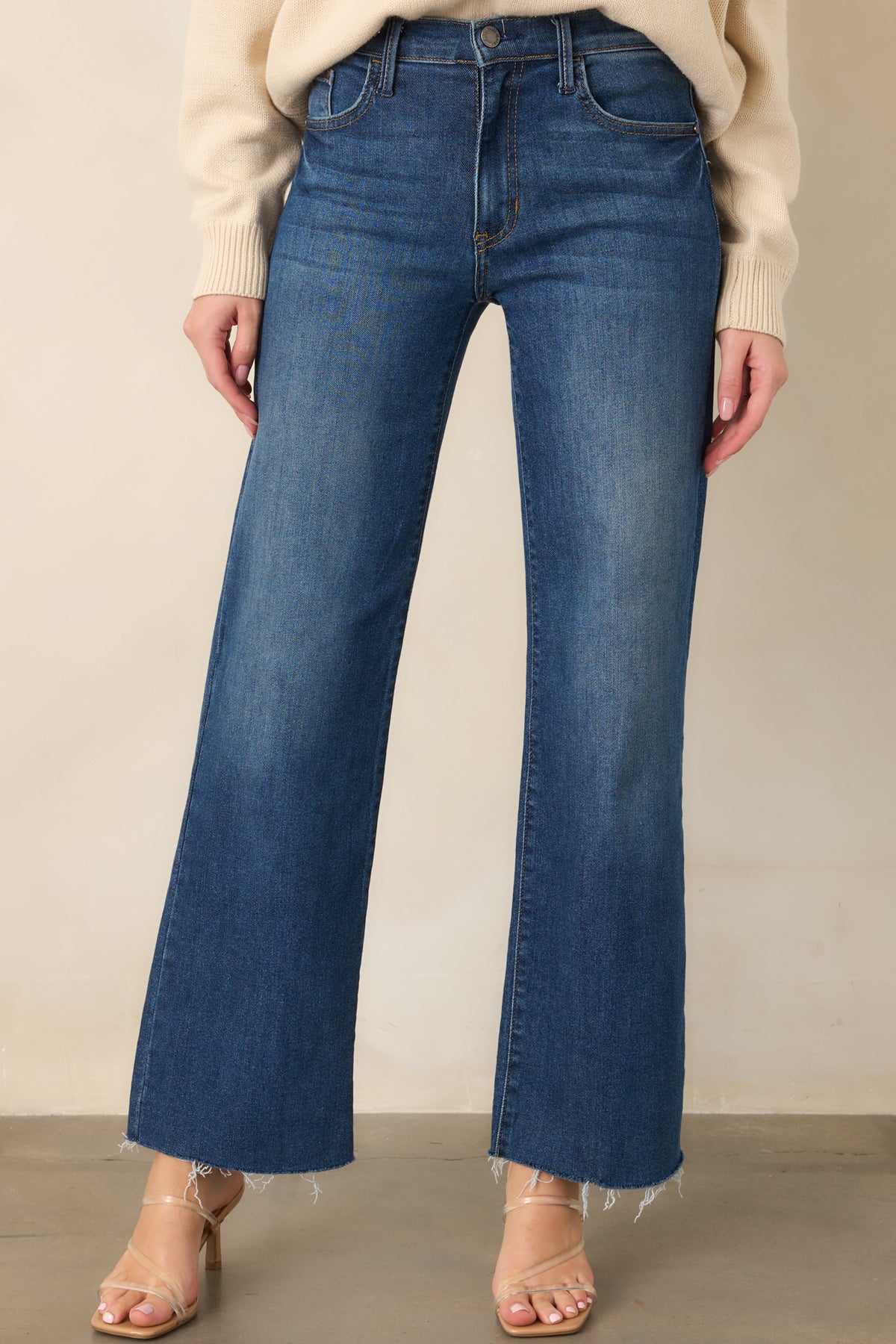 High-waist dark wash jeans featuring the front zipper and button closure with functional front pockets.