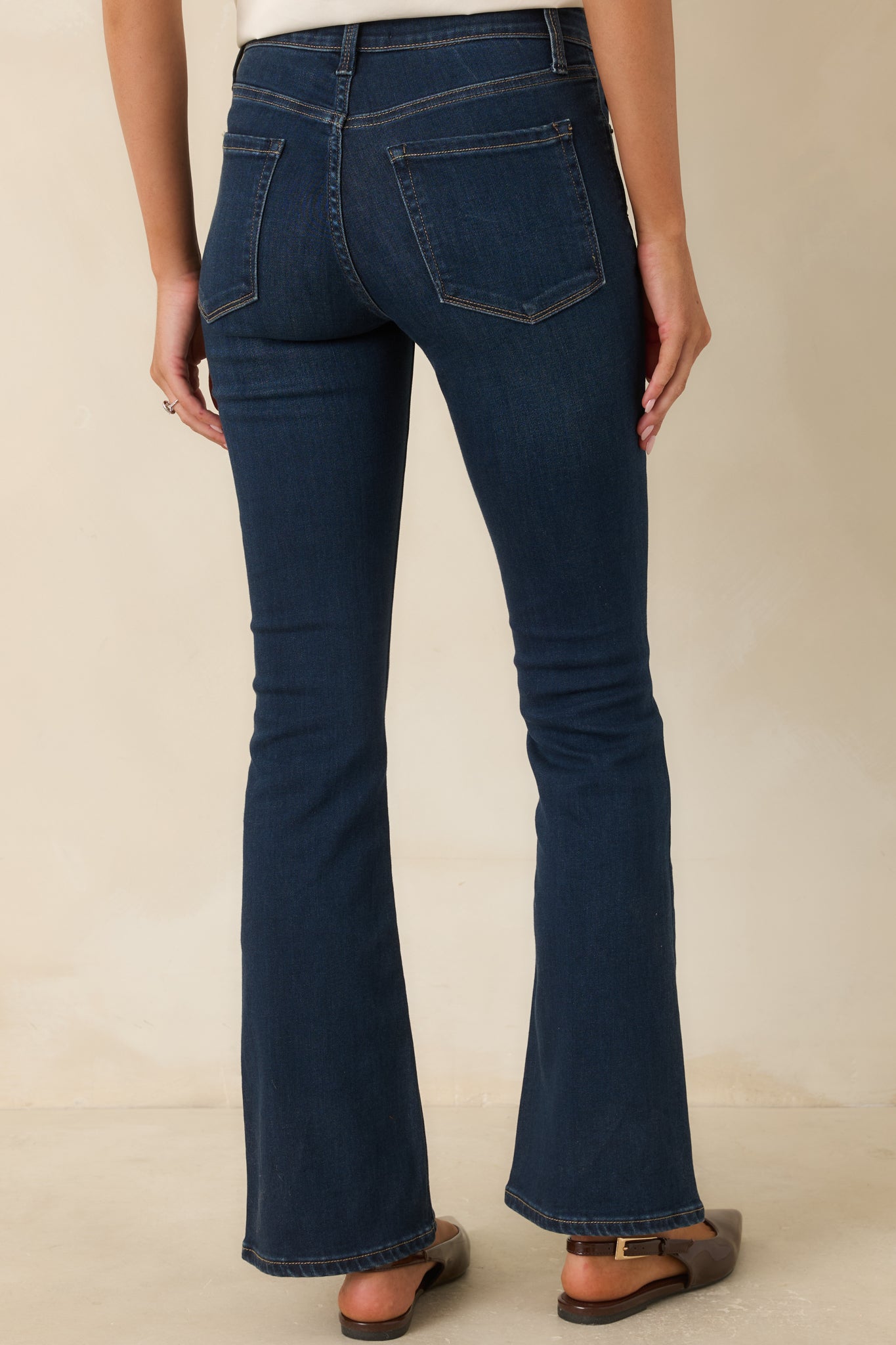 Rear view of the dark wash denim jeans featuring back pockets, a high-rise fit, and a slight flare leg.