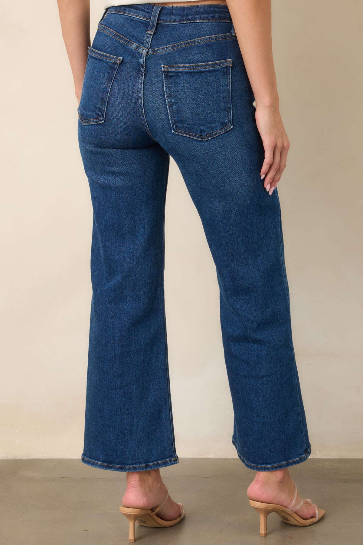 Rear view of the dark wash jeans showing the high waist, functional back pockets, wide legs, and cropped hemline.