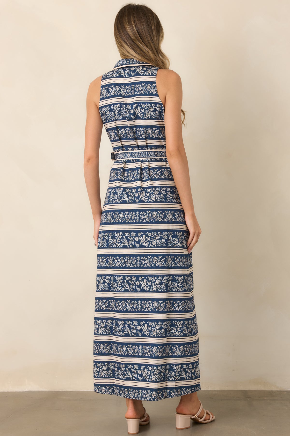 Rear of the deep blue midi dress showing the horizontal ivory botanical print and straight skirt silhouette.