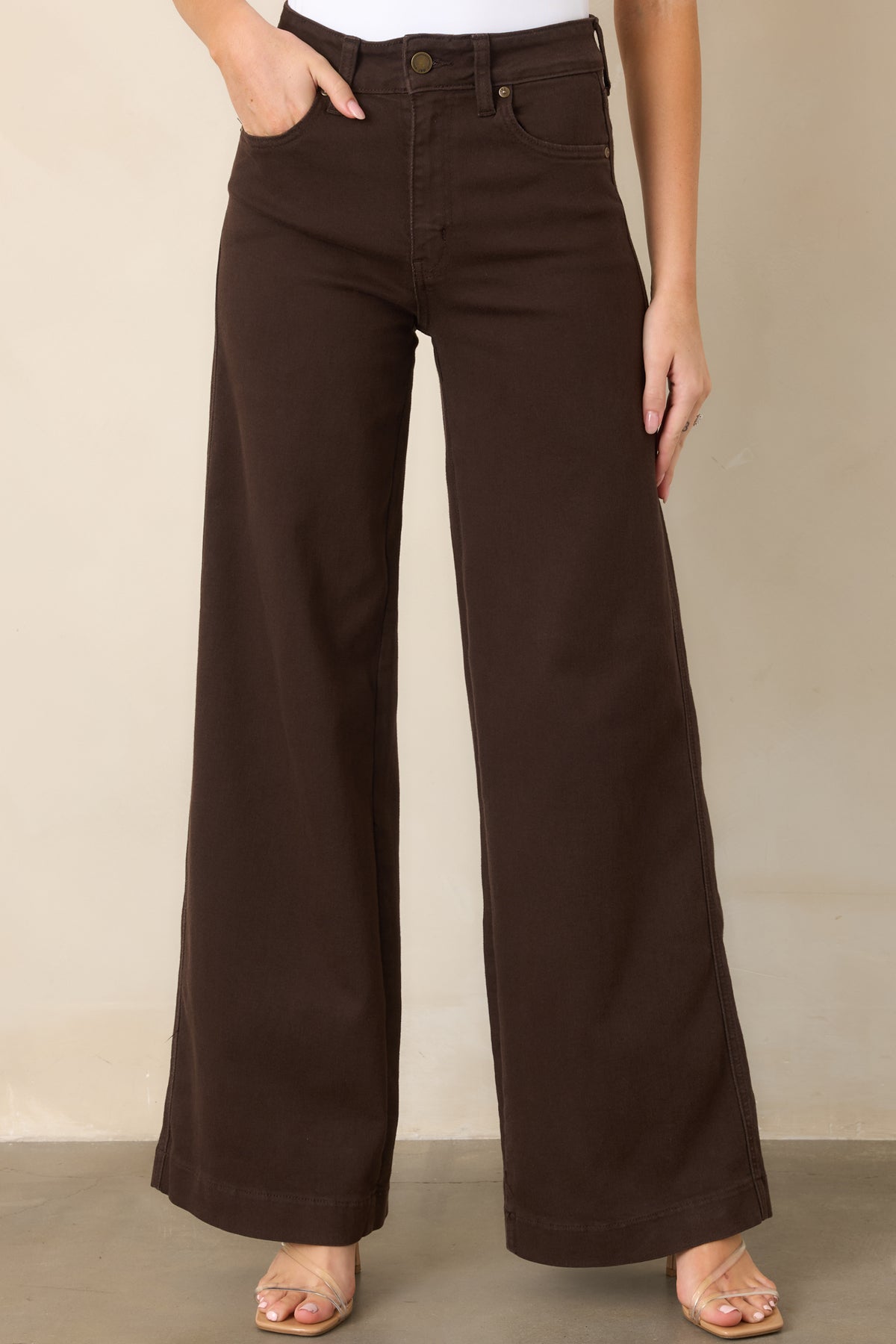 Close view of the deep brown denim highlighting the high-rise waistband, belt loops, and clean wide-leg construction.