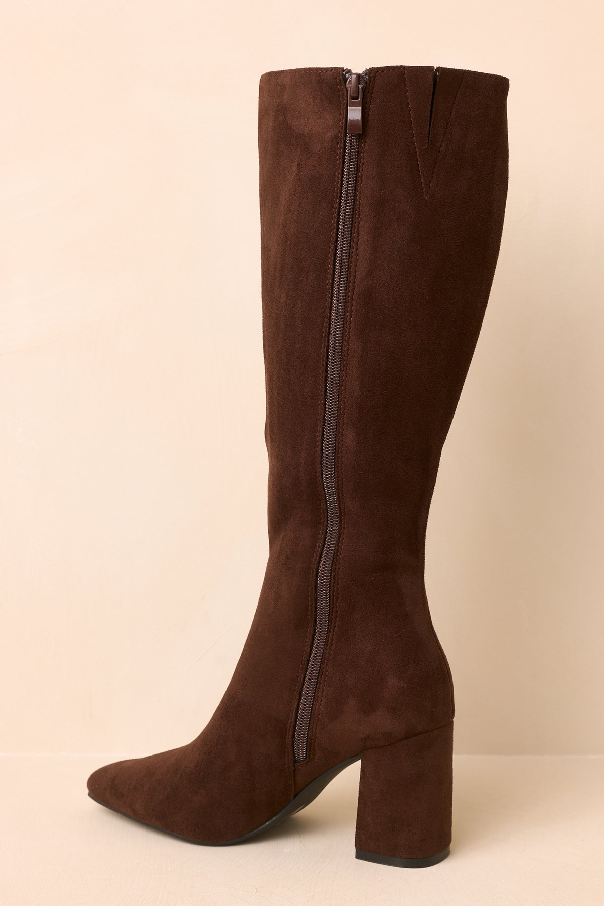 Deep brown boots highlighting the pointed toe, fitted shaft, and clean side profile.