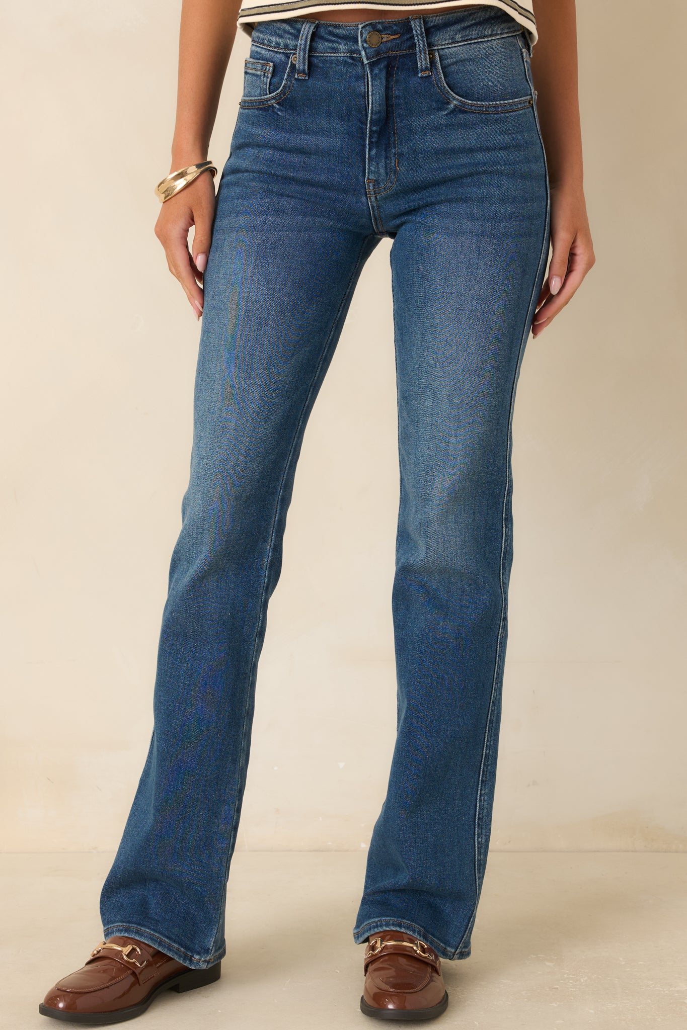Deep indigo bootcut jeans showcasing subtle fading across the upper legs, fitted contours, and a clean flare toward the hems.