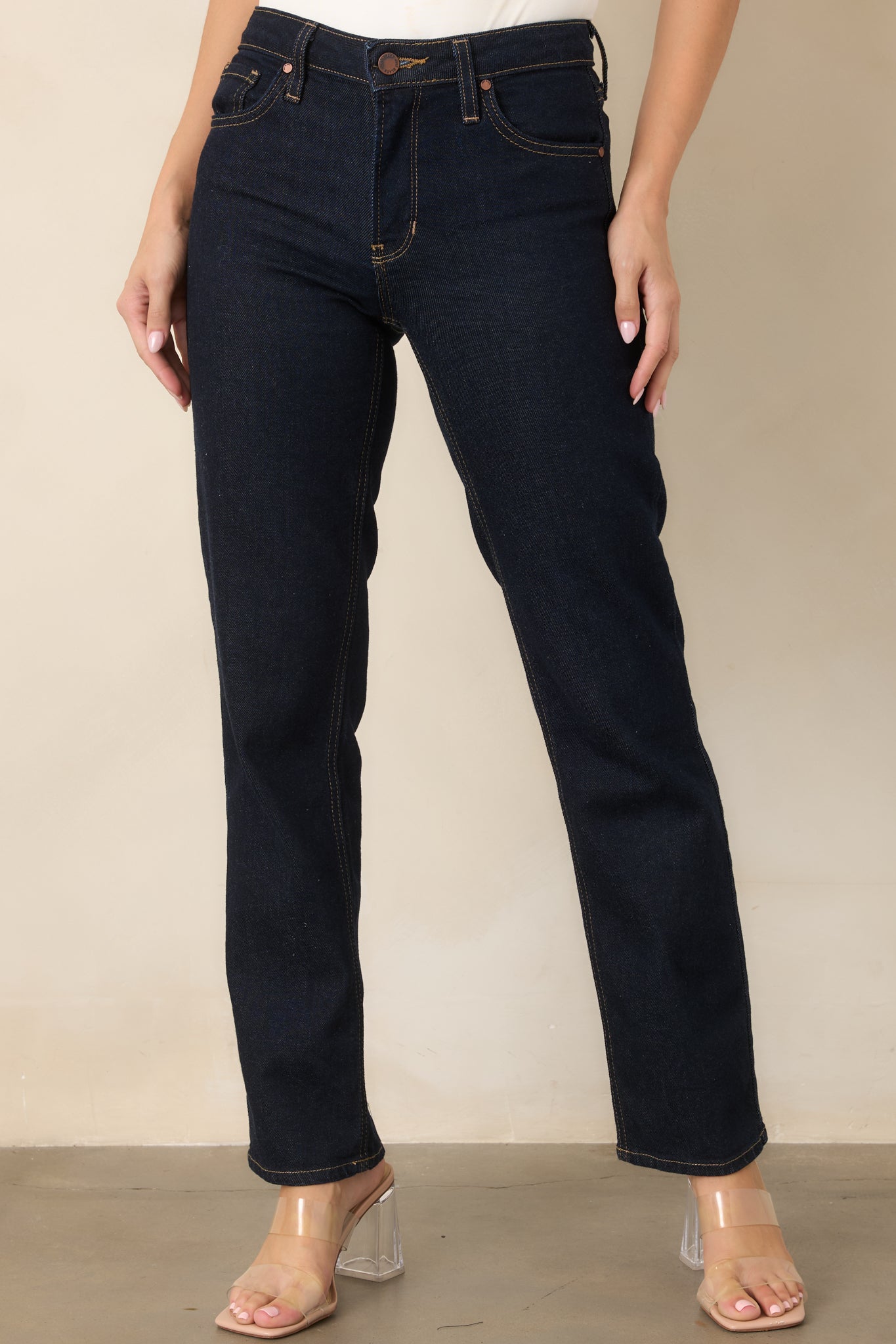 Deep indigo jeans highlighting the high-rise waistband, belt loops, and classic button-and-zip front closure.