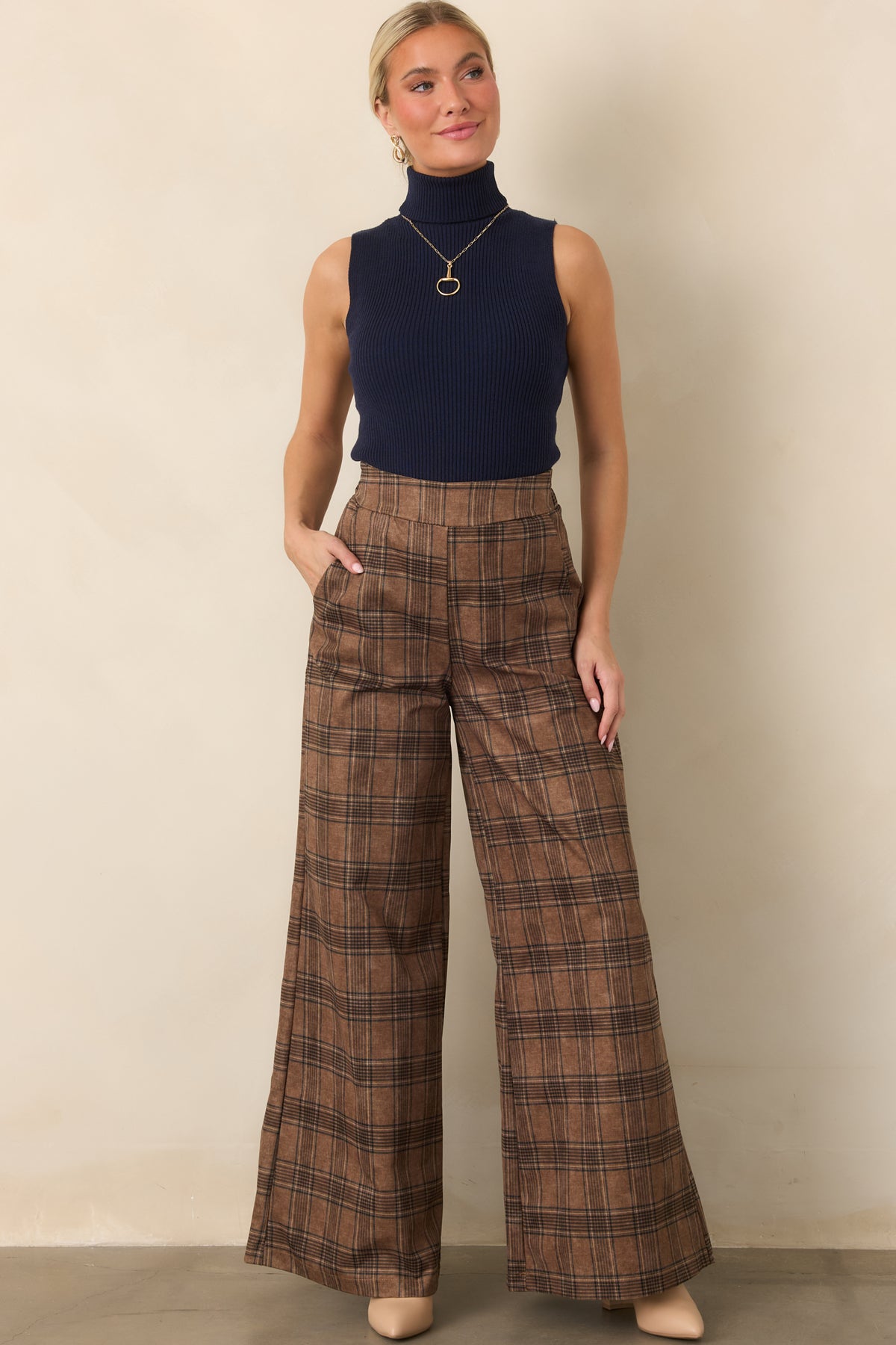 Fitted deep navy ribbed top with a sleeveless design, tall fold-over turtleneck, and versatile hip-length finish.