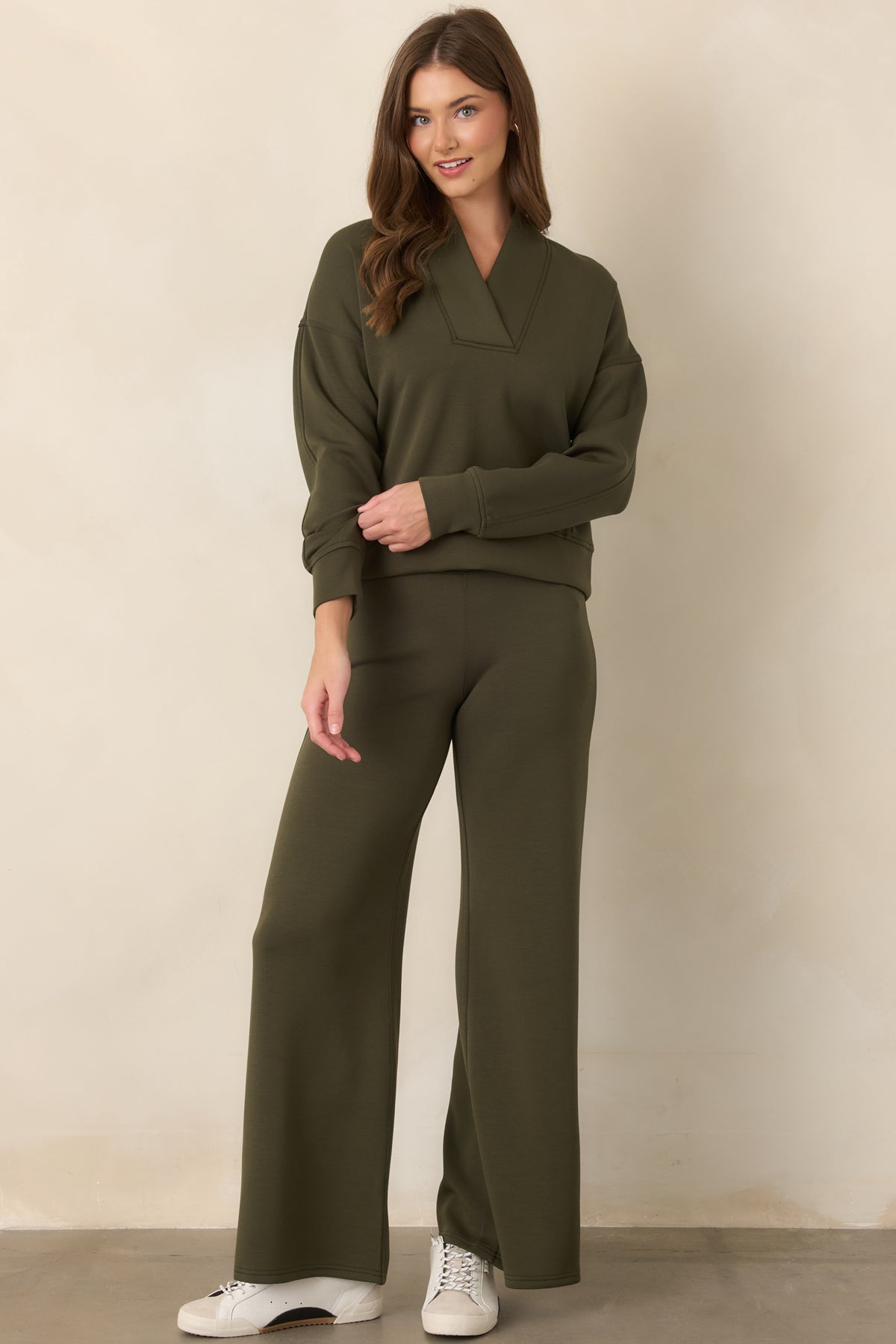 Deep olive fabric showcases the relaxed shoulder construction, long sleeves, and neatly finished banded cuffs.
