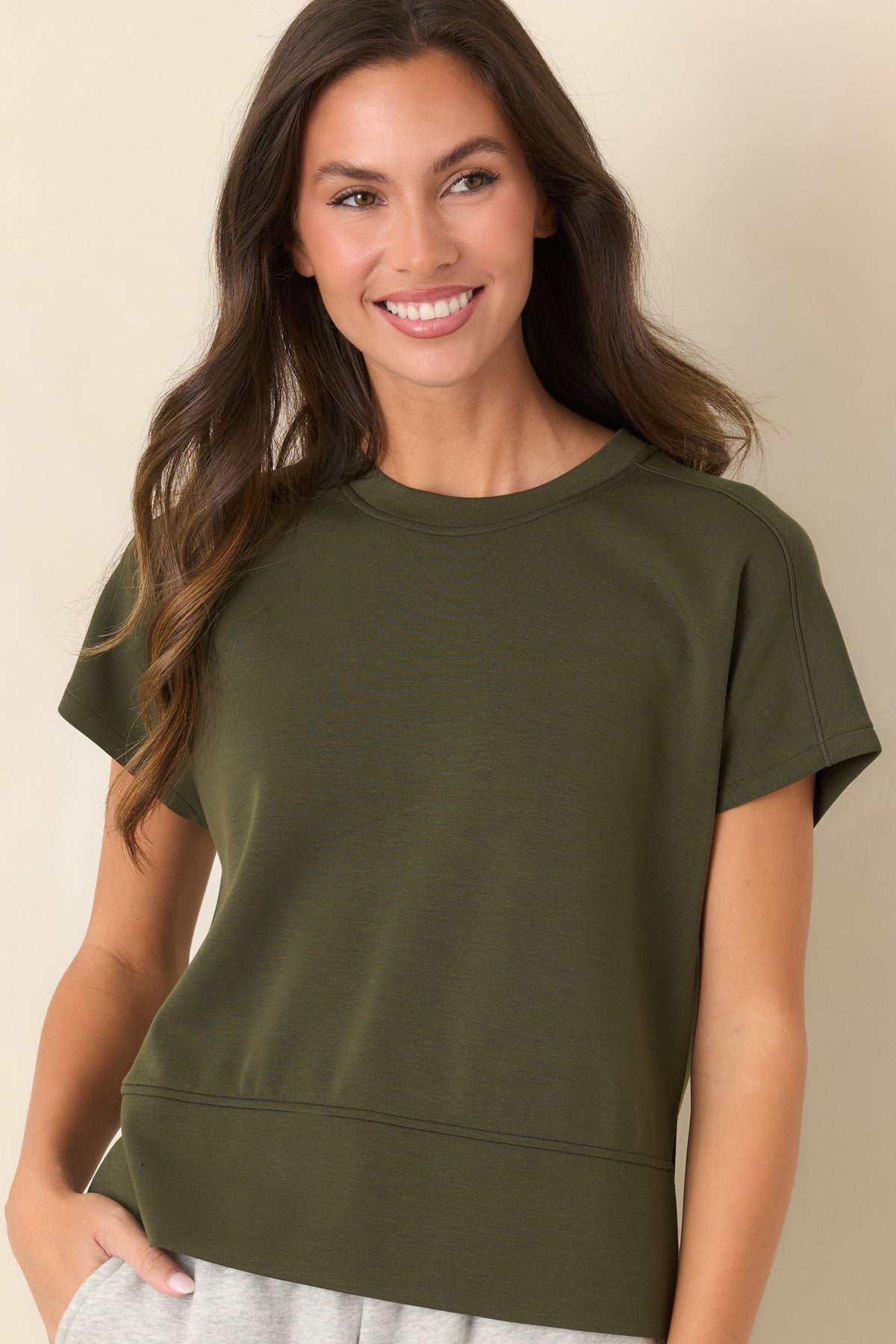 Deep olive-green top highlighting the classic crew neckline and smooth spacer fabric texture.