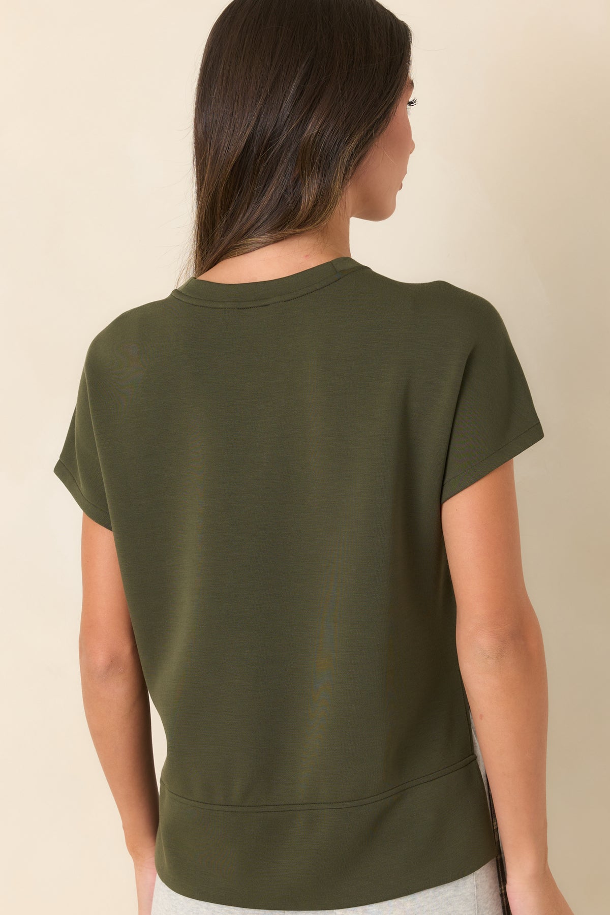 Rear of the deep olive-green top showing the high-low hem and side slit detailing.
