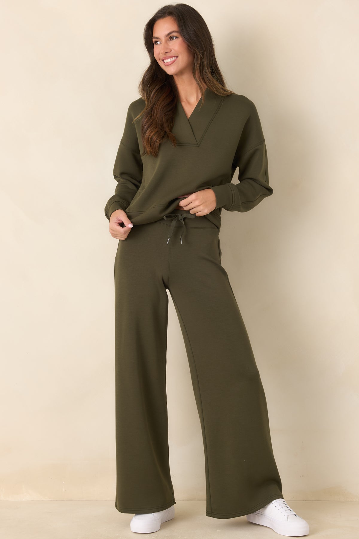 Deep olive-green top showcasing the structured V-neckline, dropped shoulders, and clean seamed detailing.
