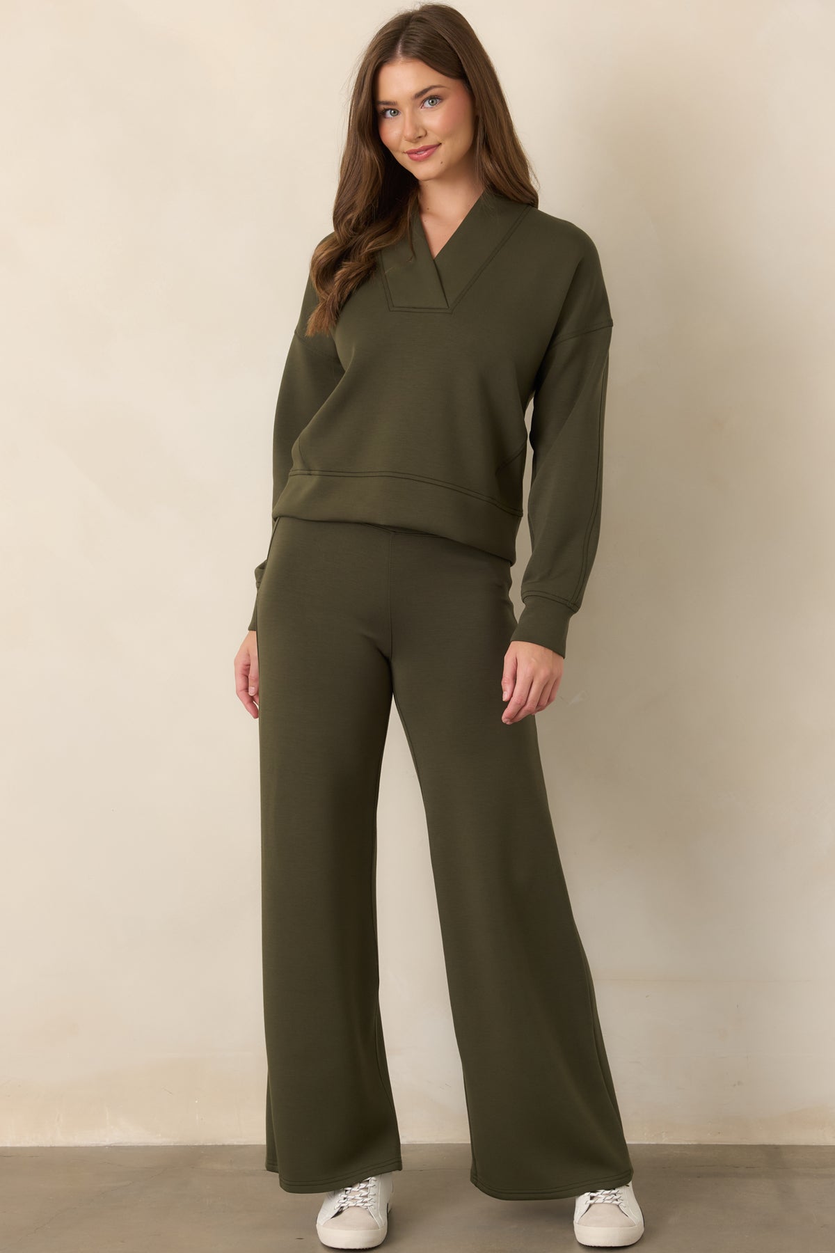 Deep olive-green top featuring a structured V-neckline, wide collar, dropped shoulders, and relaxed long-sleeve silhouette.