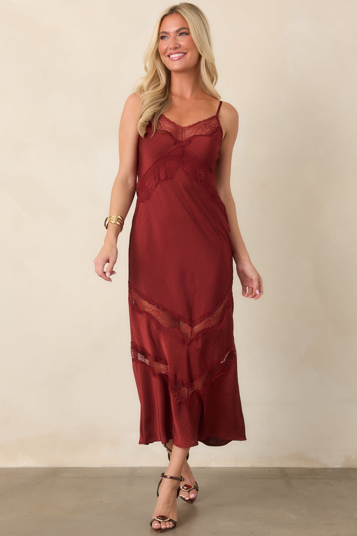 Deep red crinkled satin midi dress with a fluid silhouette, slender straps, and layered lace detailing