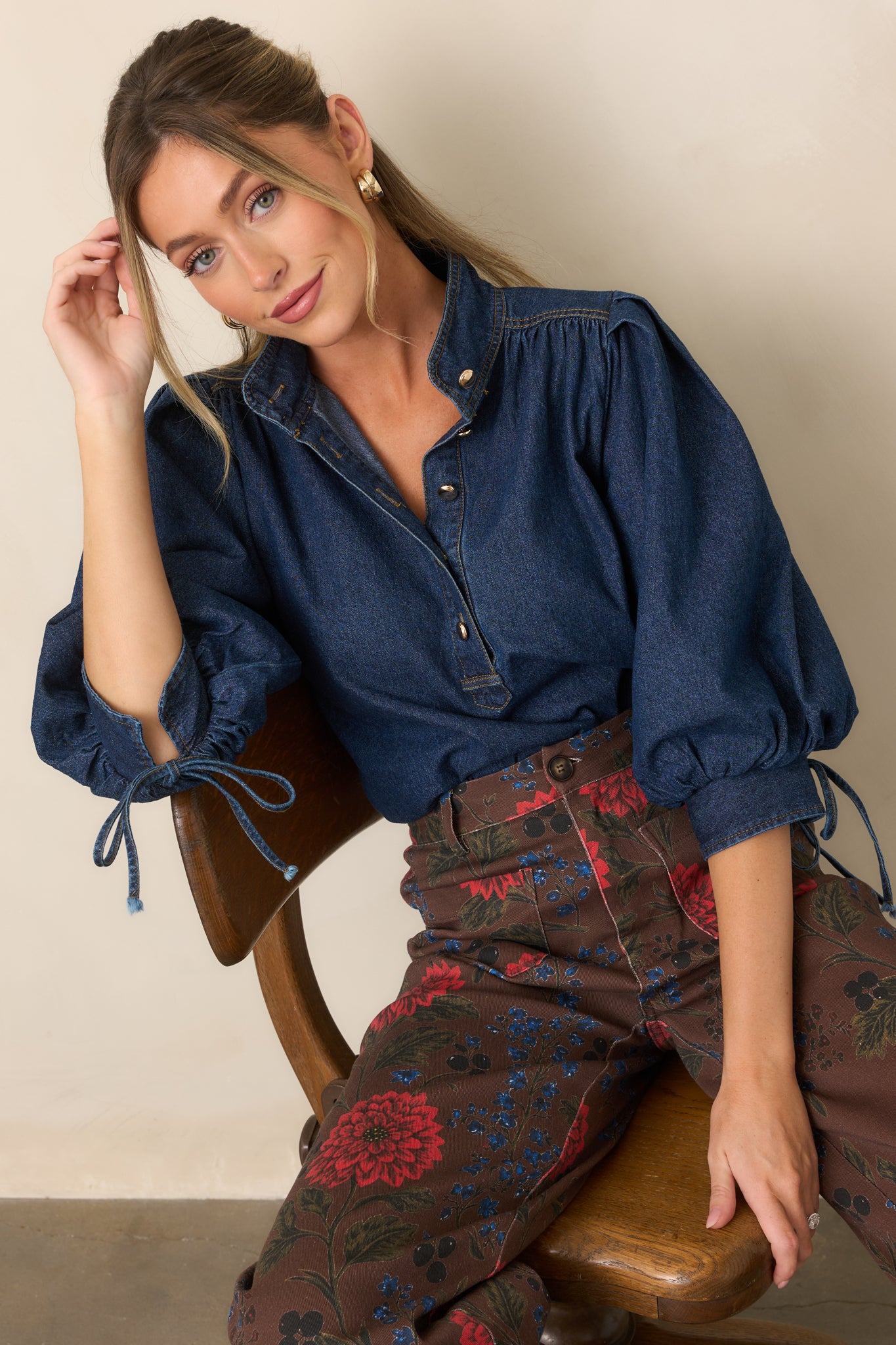 Close view of the denim top highlighting its collar, partial button placket, and gathered shoulder construction.