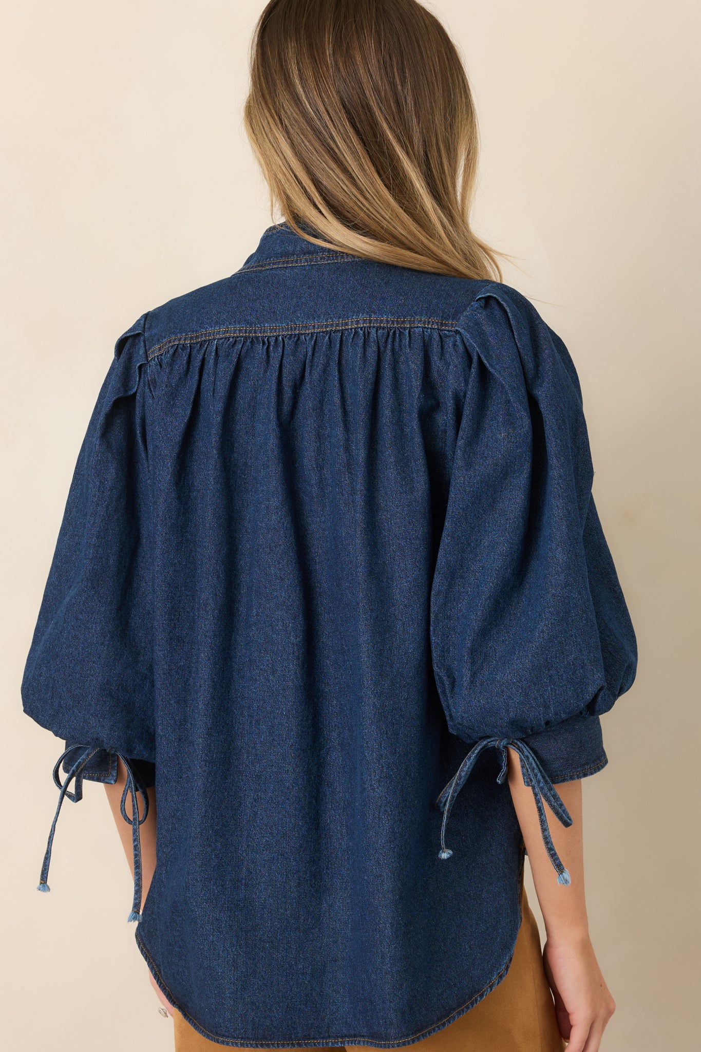 Rear view of the cotton-blend denim top showcasing its longer hem, side slits, relaxed drape, and voluminous sleeves.