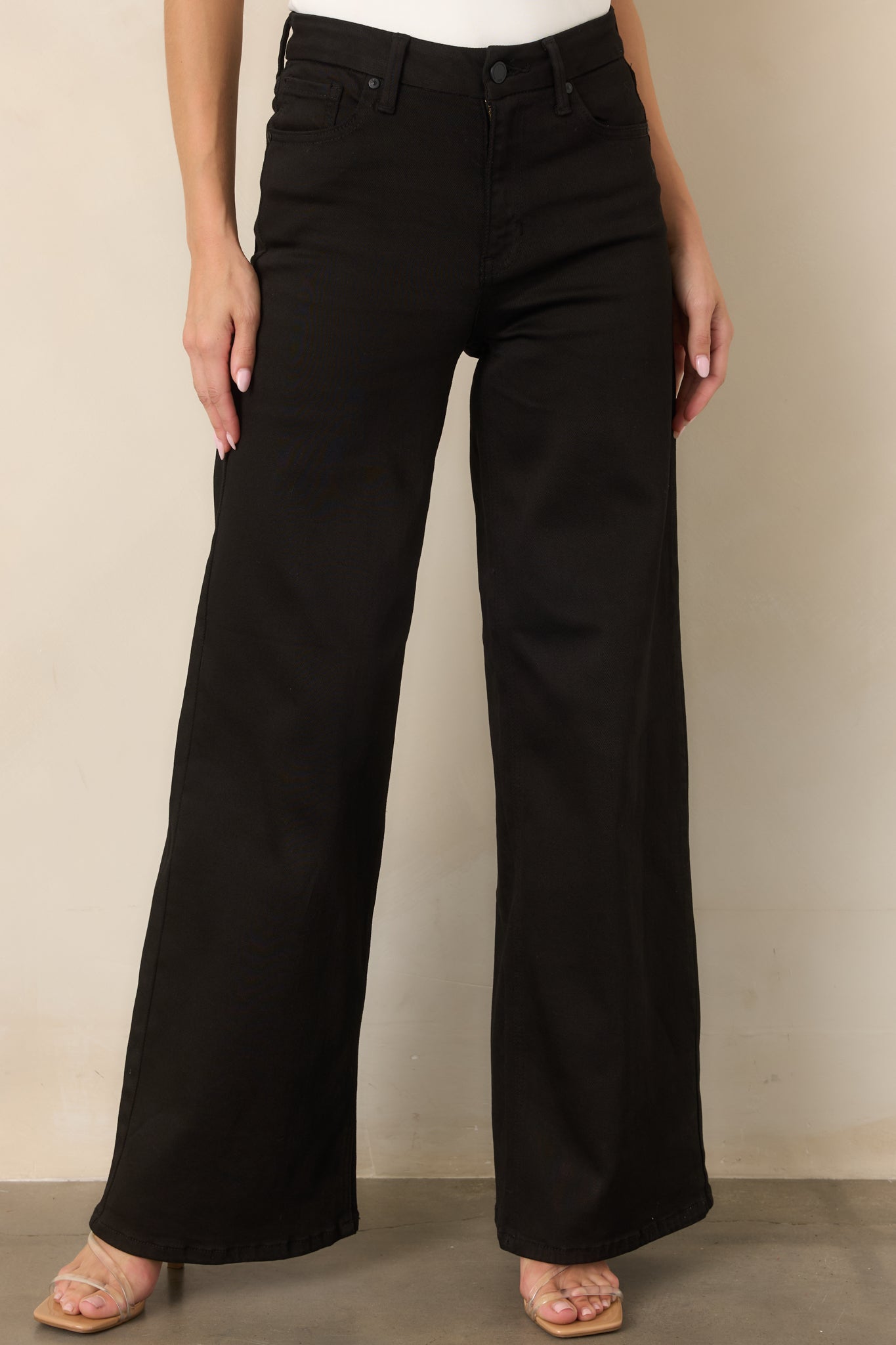 Close view of the denim waistband, belt loops, button-and-zip closure, and classic front pocket detailing.