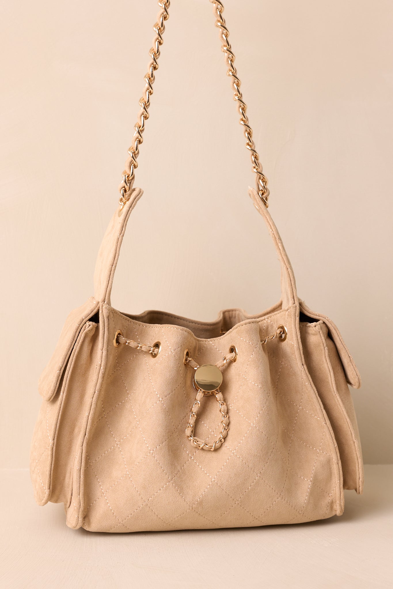Detail crop emphasizing purse strap with faux leather cord interlaced with gold chain.
