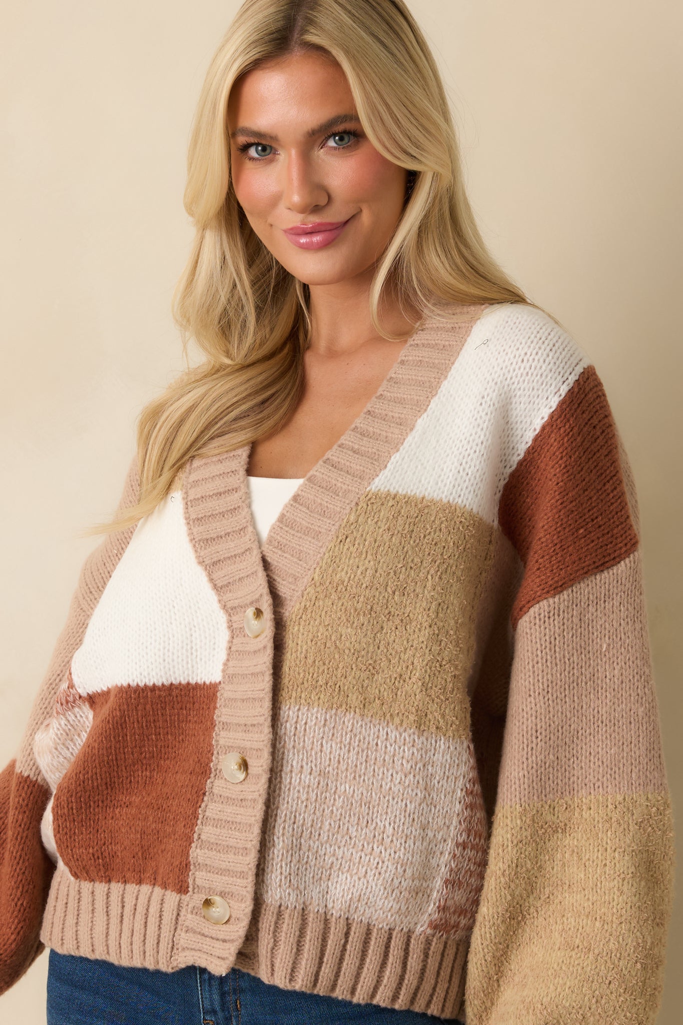 Detail of front buttons and ribbed balloon sleeves on taupe knit cardigan.