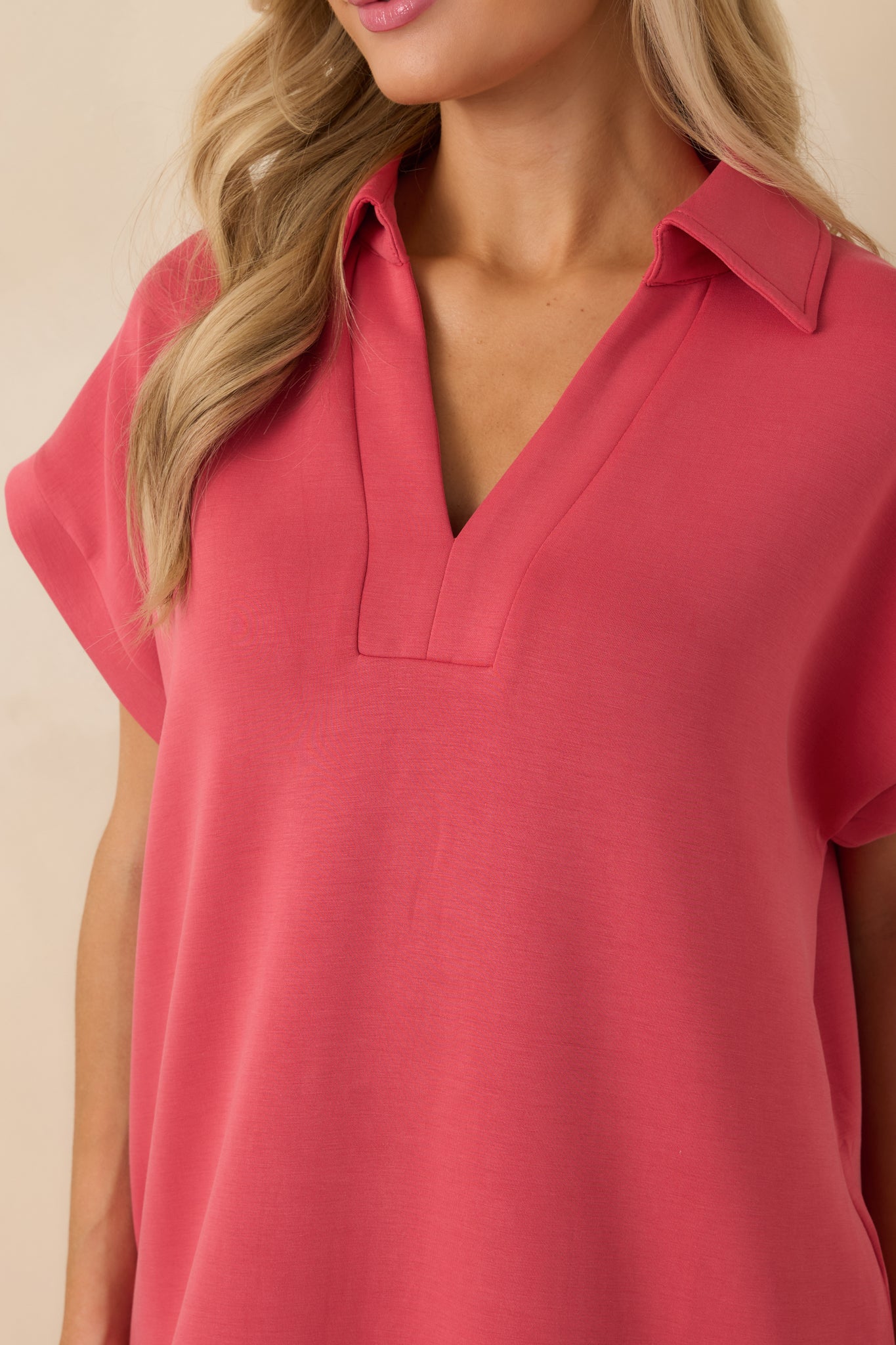 Close detail of the coral pink fabric highlighting the smooth, buttery soft texture and collar construction.