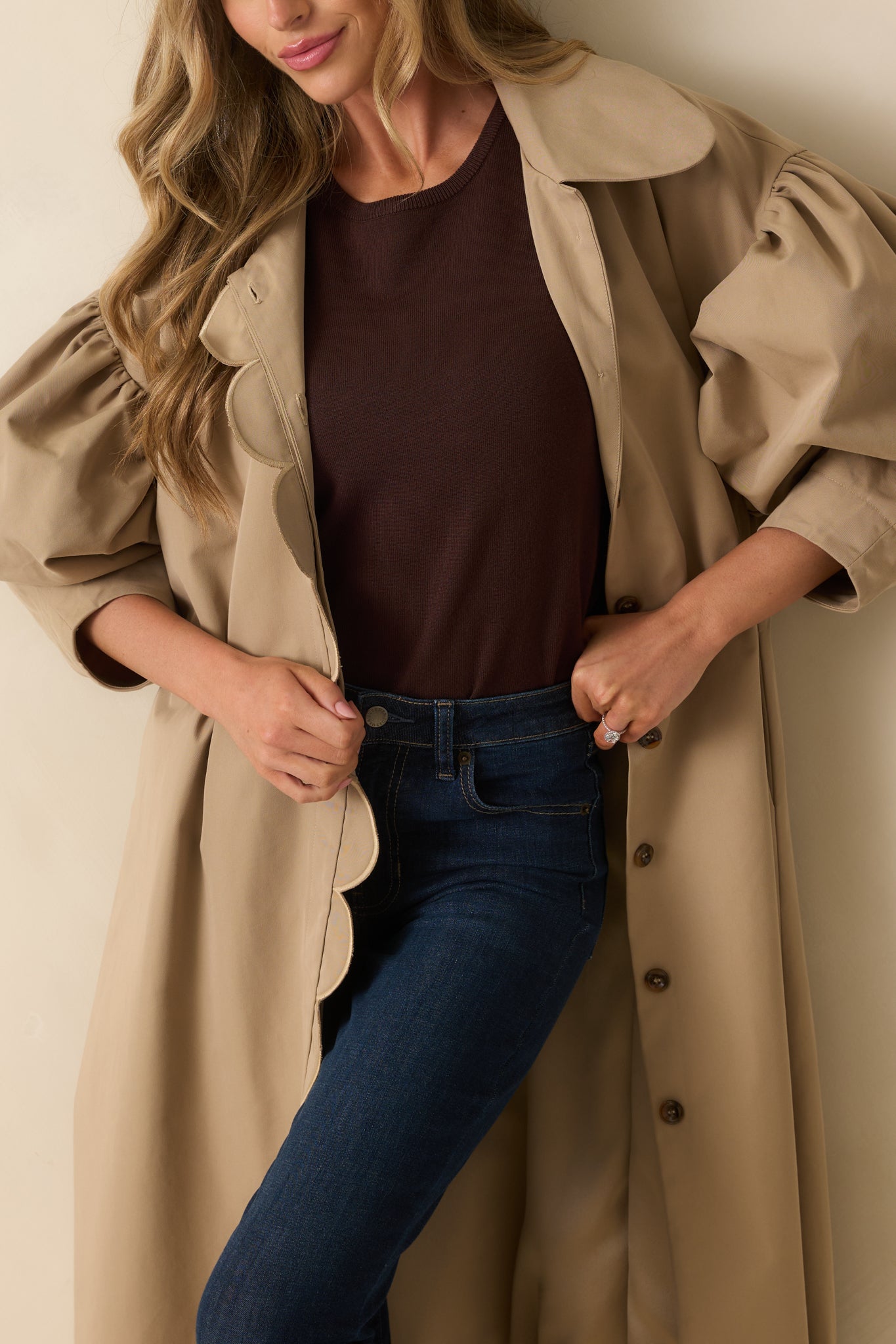 Detailed view of the khaki coat’s scalloped edge trim and button design.