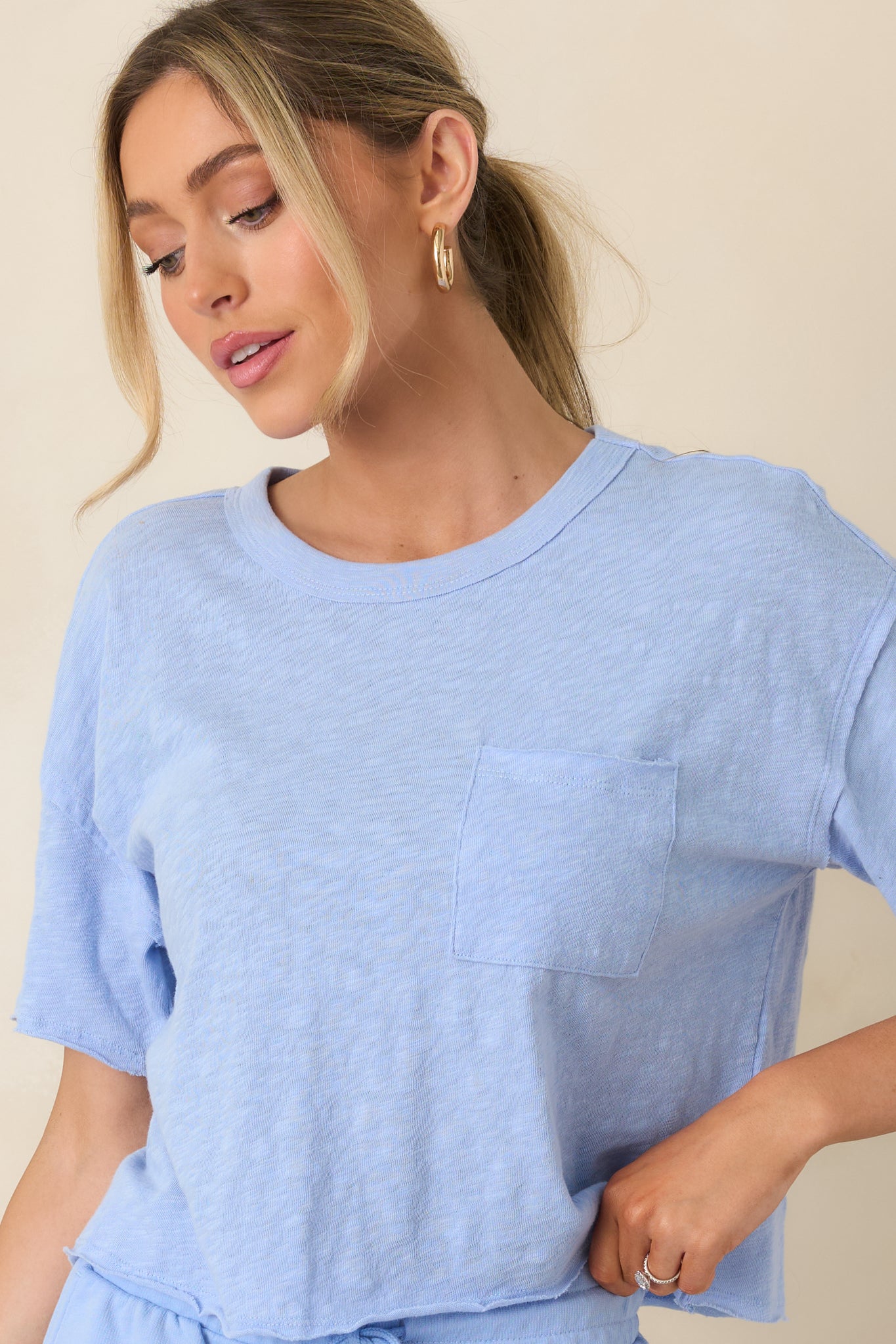 Detail of the slightly cropped hem and soft fabric in the relaxed-fit light blue tee.