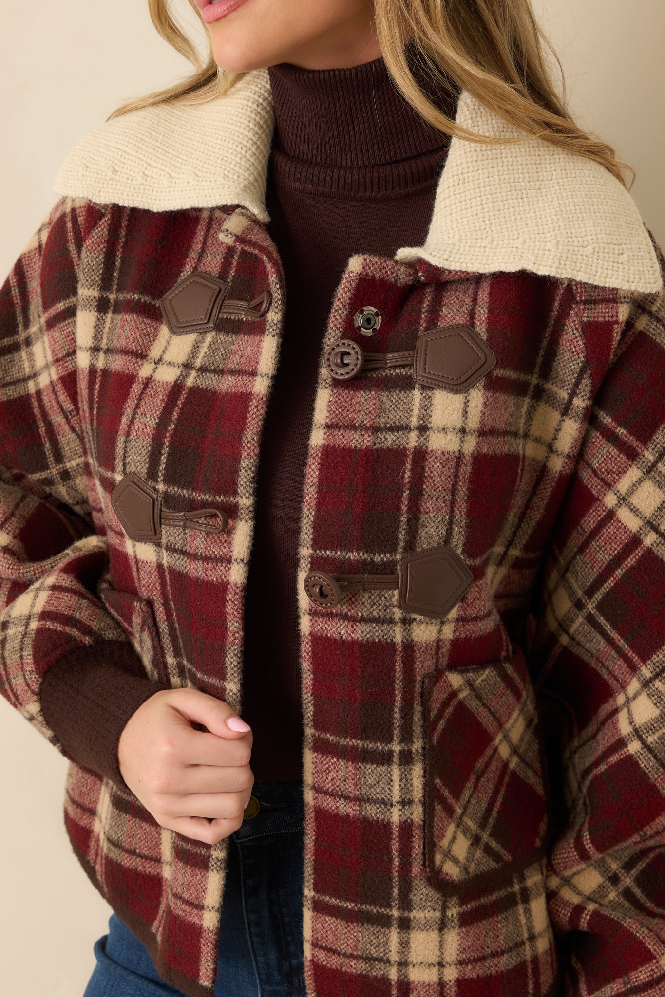 Close-up detail of plaid fabric, button closures, and knit collar texture.