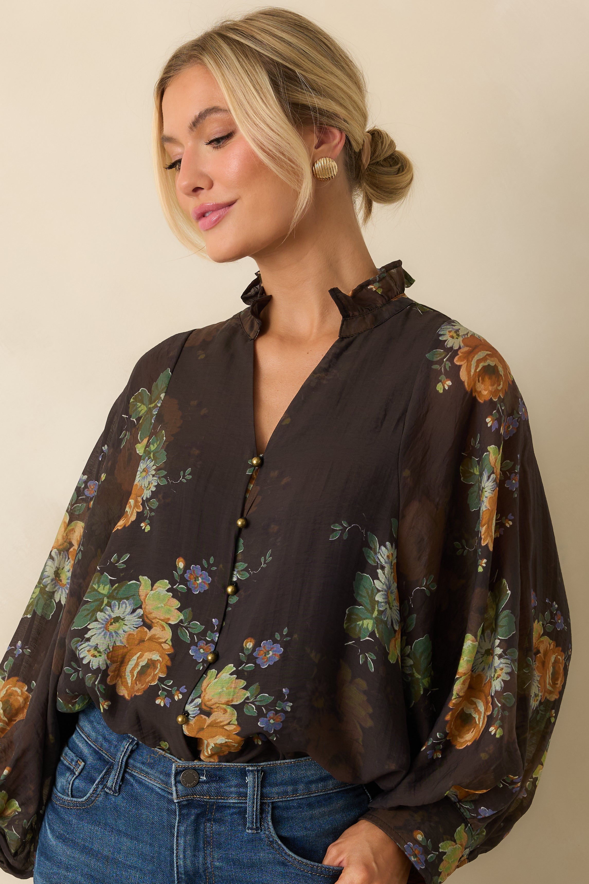 Detail of the buttoned cuffs and peasant sleeve design on the floral blouse.