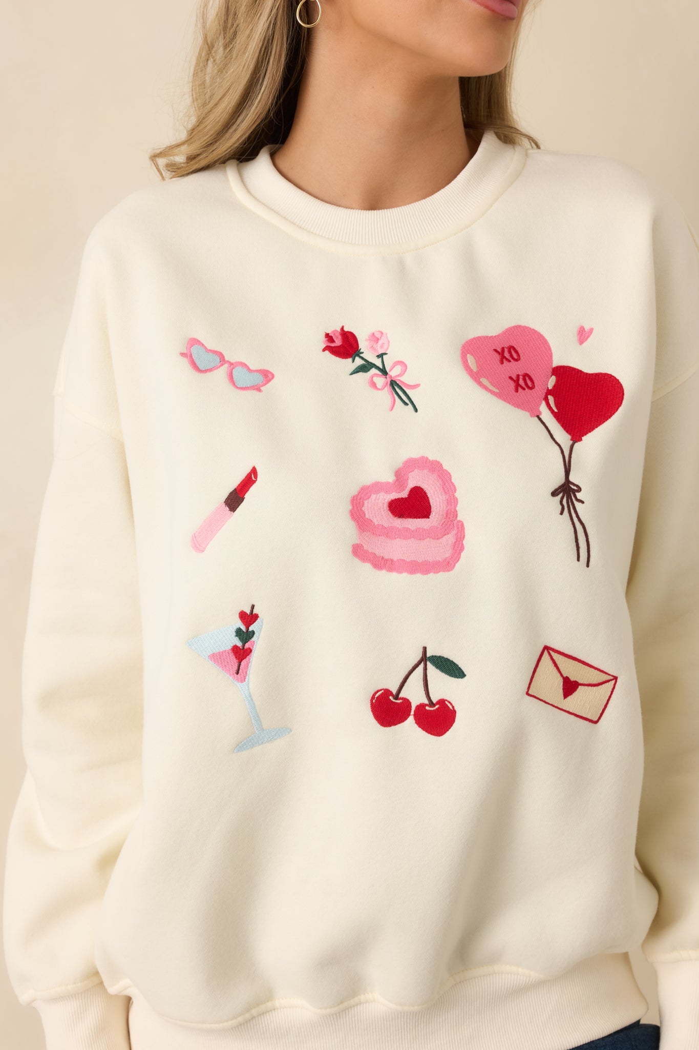 Close-up detail of the colorful Valentine-inspired graphics and ribbed trim on the ivory crewneck sweatshirt.
