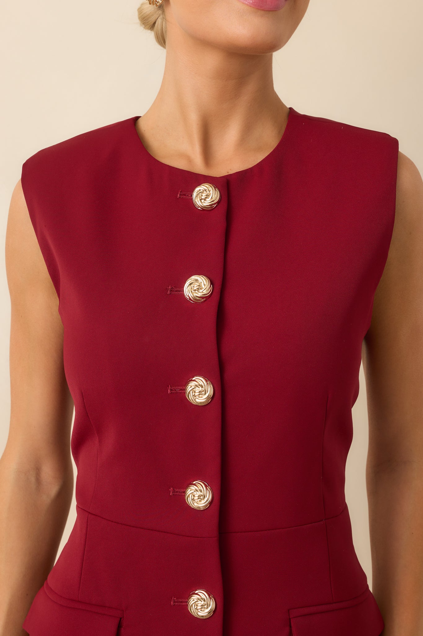 Close-up detail of a gold button and surrounding fabric texture on the burgundy mini dress.