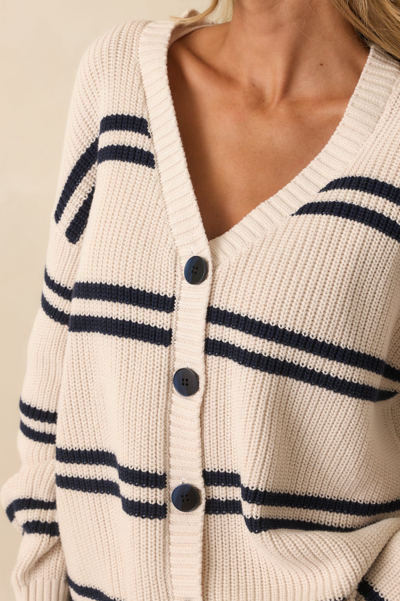 Tight detail of the ivory ribbed knit fabric with navy stripes and front buttons.