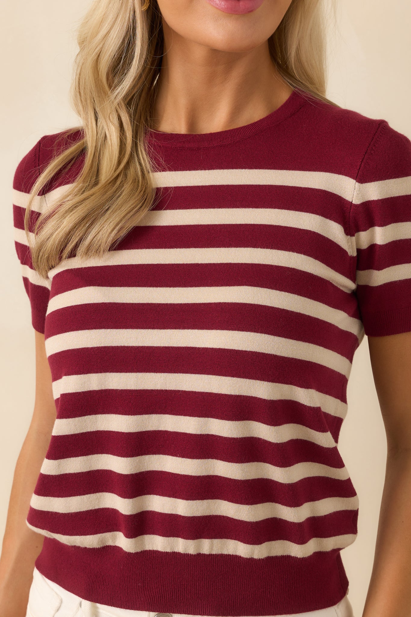 Close-up detail of the ribbed trim and burgundy and beige stripe pattern in the knit fabric.