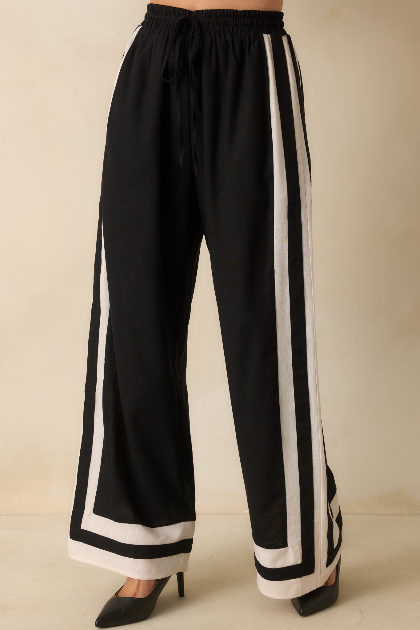 Detail on the flowing wide-leg silhouette and ivory and black trim pattern along the pant legs.