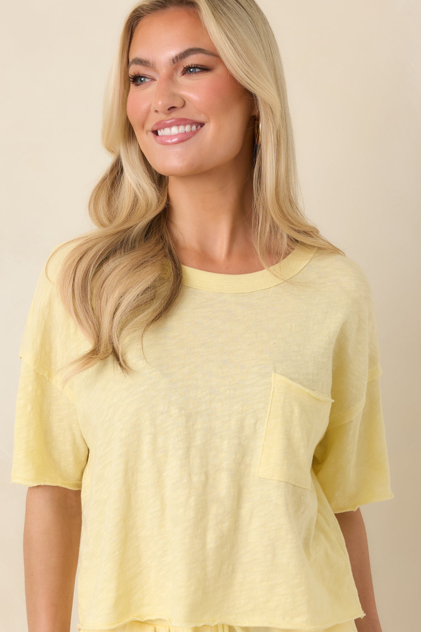 Detail view of the vibrant yellow cotton fabric and neatly finished stitching along neckline and sleeves.