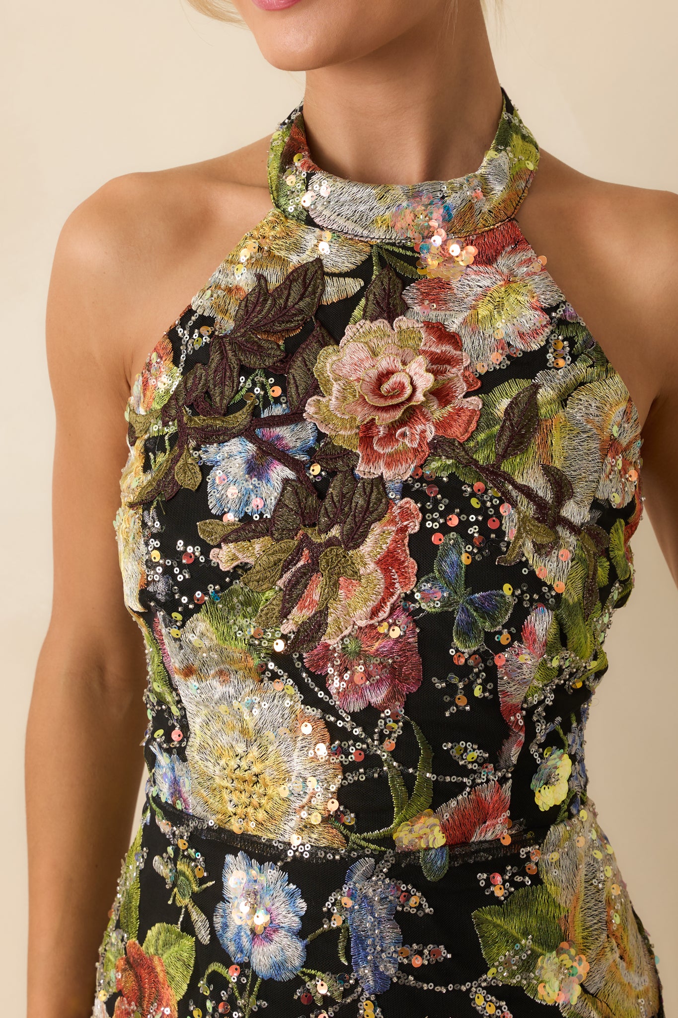 Detailed close-up of black floral sequin fabric showing intricate sparkle, floral motifs, and smooth lining.