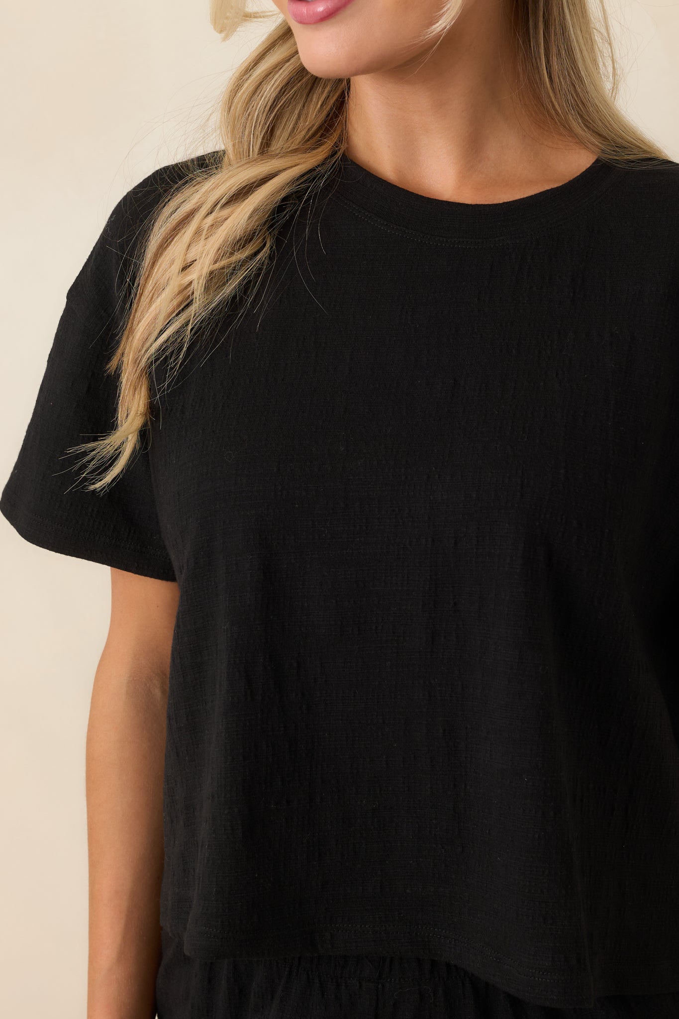 Detailed close-up of black top highlighting textured fabric and refined stitching.