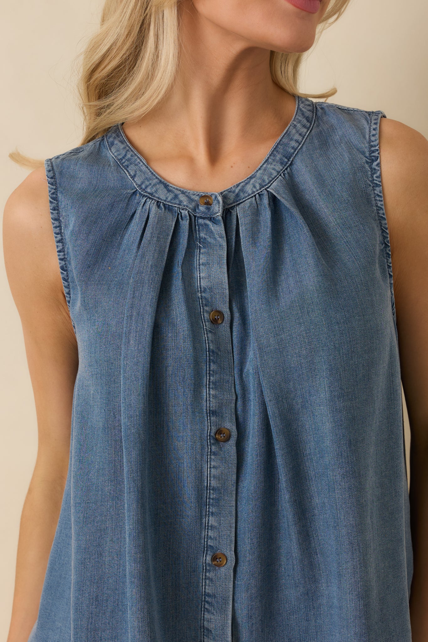 Detailed close-up of the chambray-style fabric, gathered neckline, and button-front hardware on the sleeveless top.